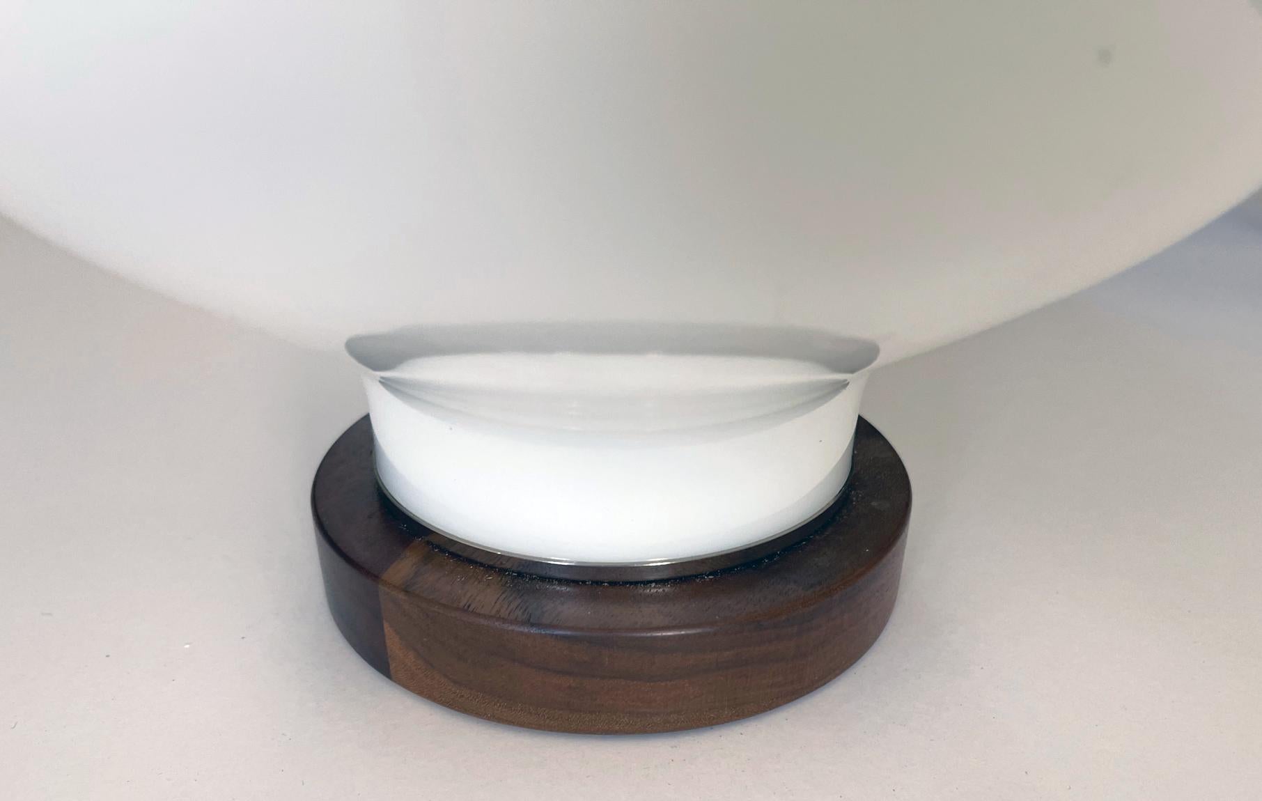 each bulbous lamp of white cased glass fitted with a walnut neck and base.