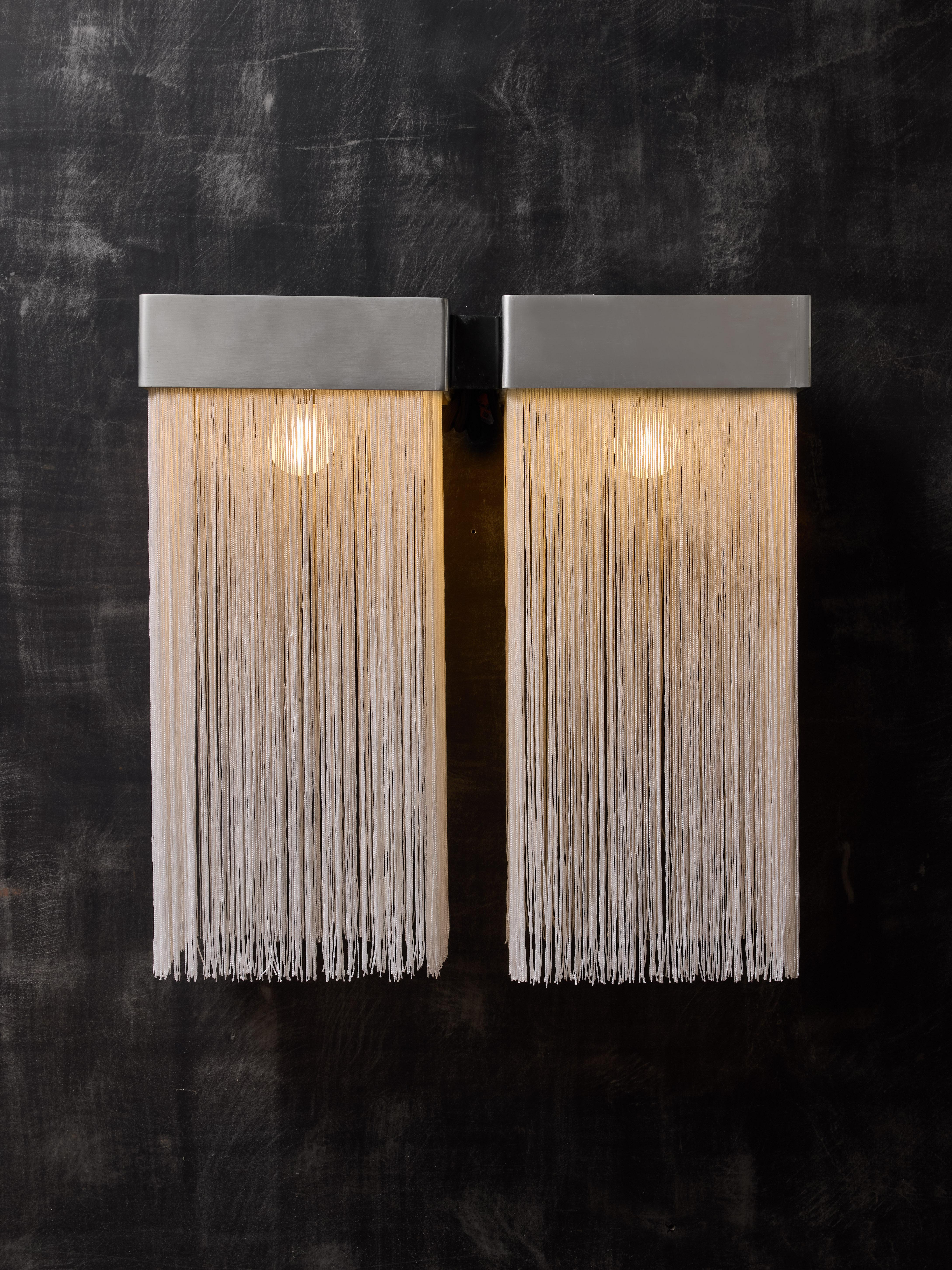 Pair of stunning wall sconces model 259/2 designed by Massimo Vignanelli and made by Gino Sarfatti's Arteluce in 1964.

Each sconce is made of two aluminium square frames from where hang fabric fringes surrounding the light sources. Both frames are