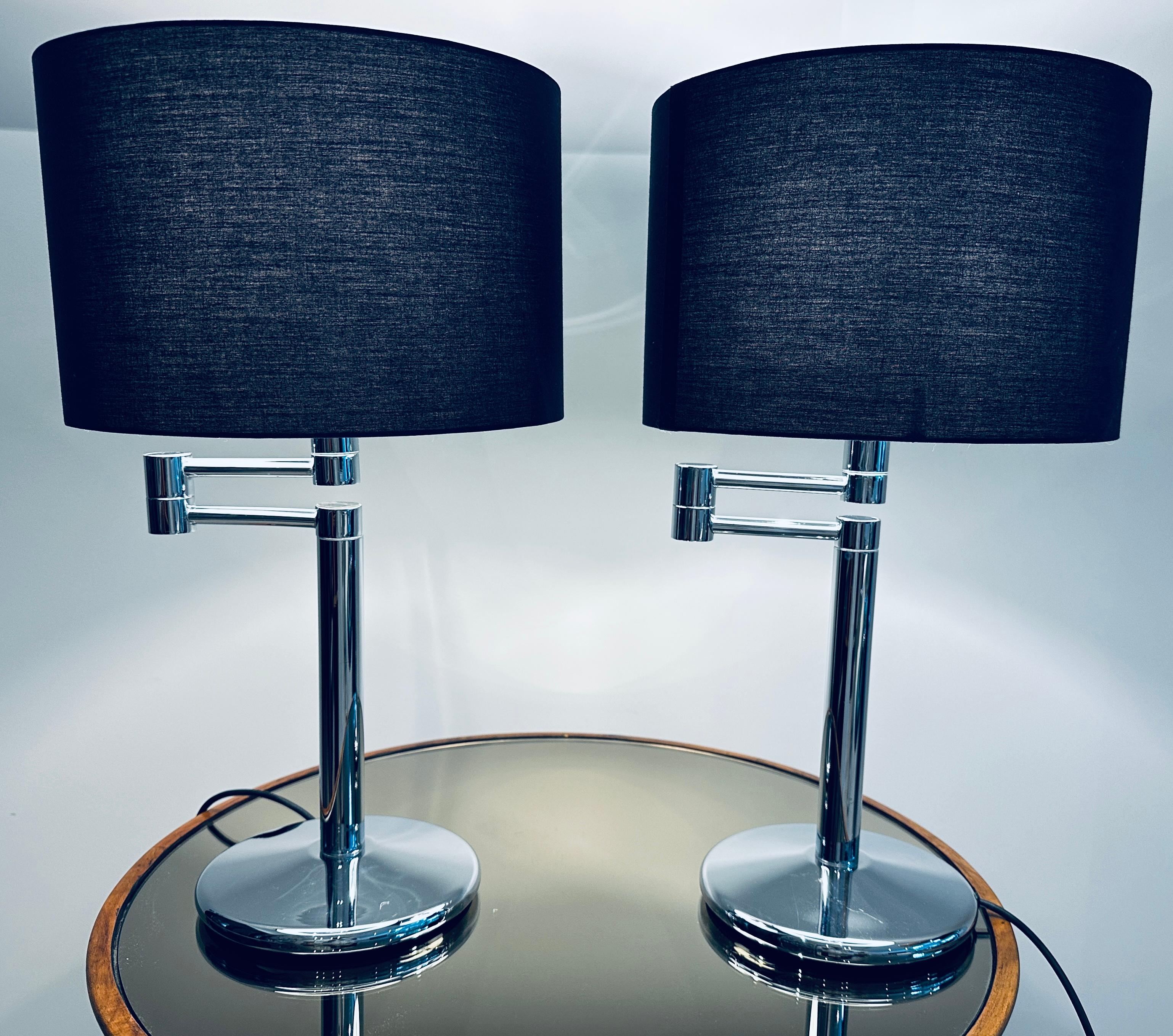 Pair of 1970s American, swing-arm, chromed-metal, table lamps attributed to Walter Von Nessen because of their style and functionality.  The circular base with smooth curved edges has a central supporting column rather than one to the side.  The arm