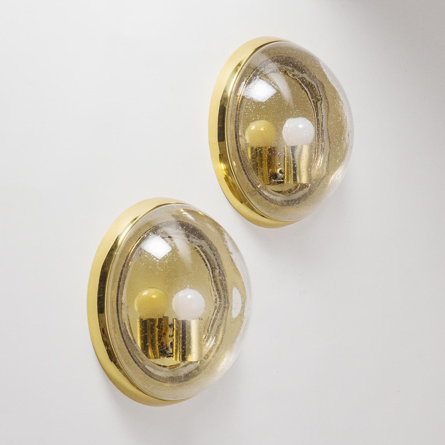 Large pair of brass 'bullseye' wall or ceiling lights by Hillebrand, Germany, 1970s. The blown clear glass domes are filled with small bubbles and have a slightly irregular surface contrasting nicely with the smooth brass hardware. Very good