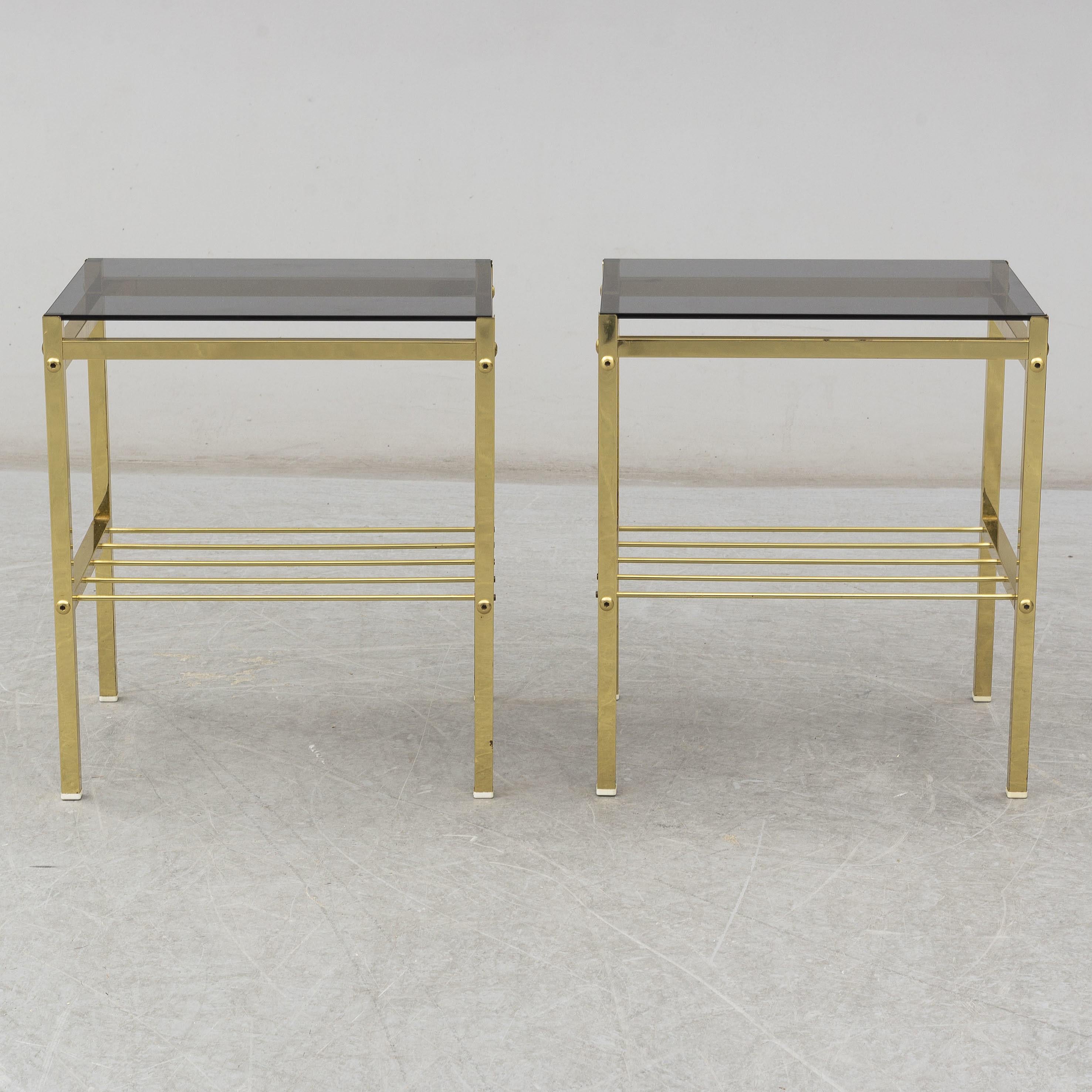A pair of bedside / side tables / nightstands tables in brass with original smoked glass tops from the 1970s.
  