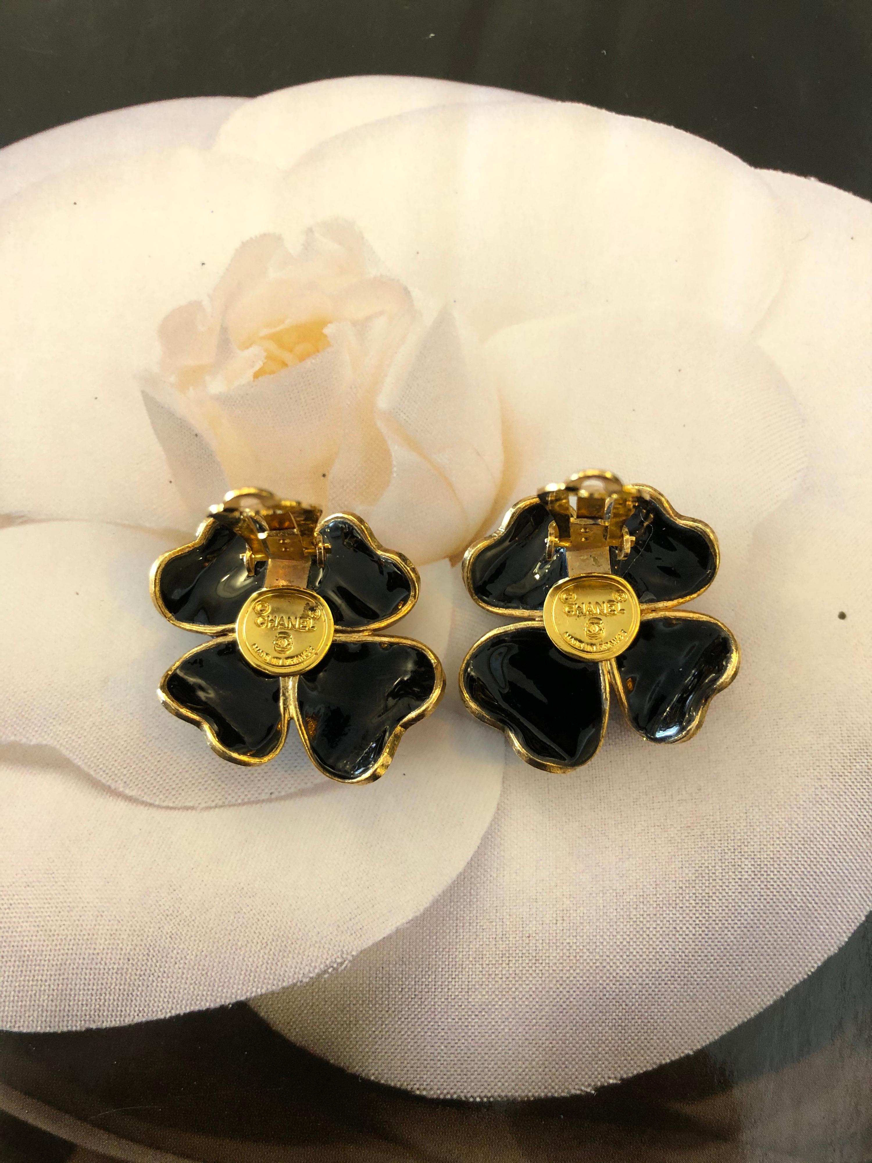 Rare 1970s Chanel gold toned earclips featuring four black gripoix clover leaves and a red coral center. Gripoix is made by pouring molten glass into a mold using a sophisticated technique for setting enameling colored, cast glass in intricate metal