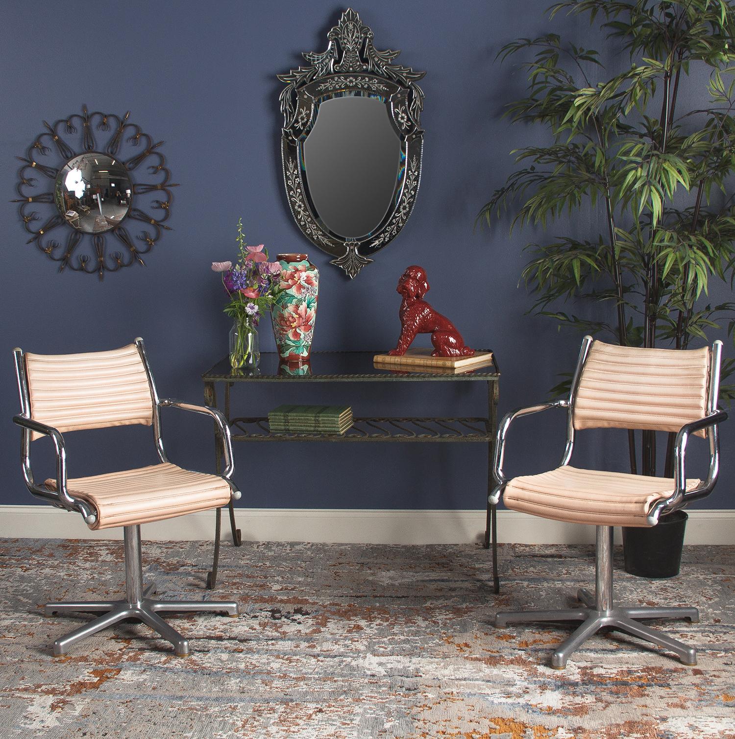 Olymp is a German-based company that specializes in designing hair salon furnishings. The pair of vintage armchairs are made of polished chrome metal with salmon pink vinyl seats. The chairs have curved armrests and rest on a five-foot pedestal