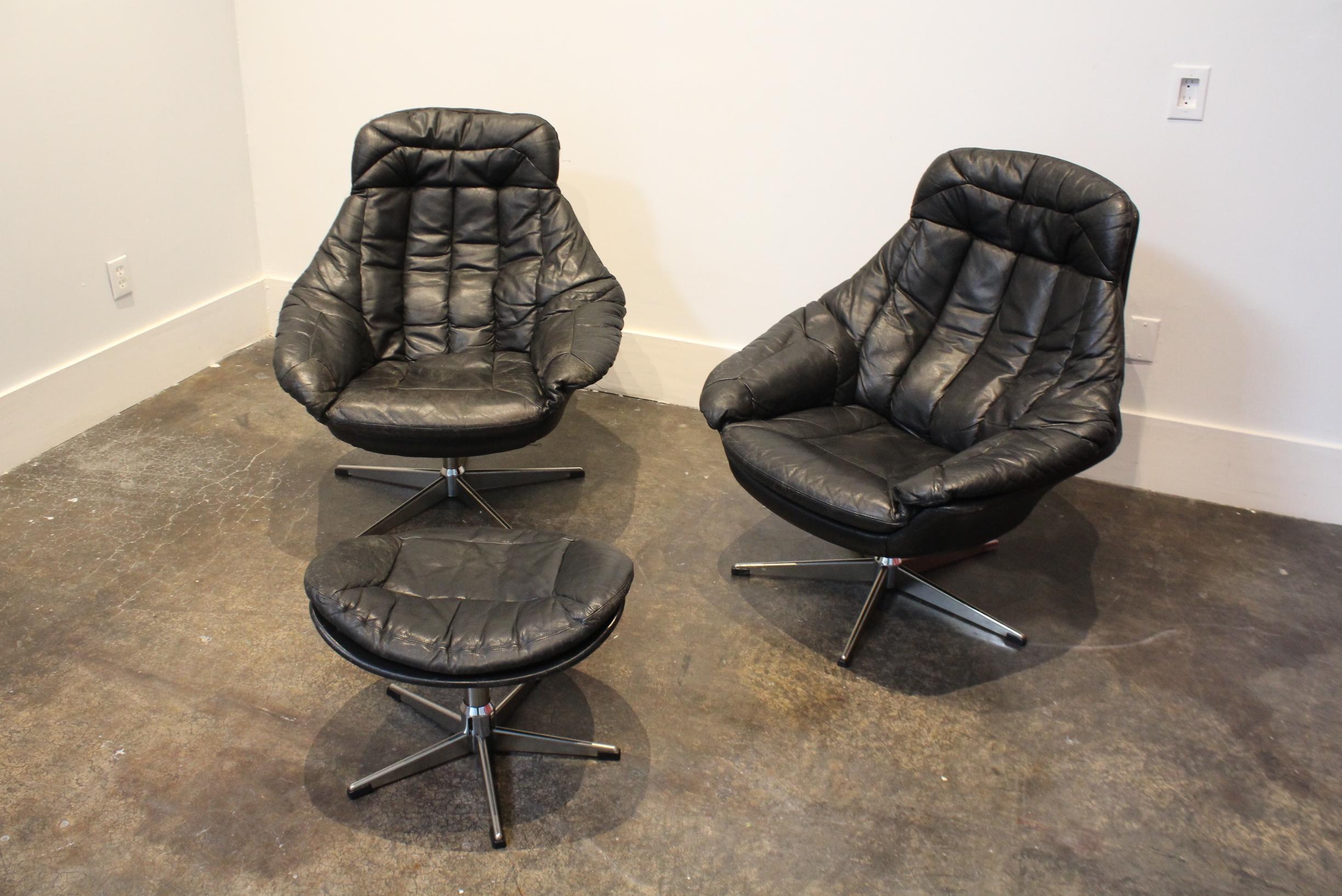 Beautifully-designed, 1970s swivel lounge chairs fully wrapped in black, leather jacket-style leather. In good condition with beautiful wear/light crackling/patina to leather but no major damage or holes. Feet are metal/chrome with very light