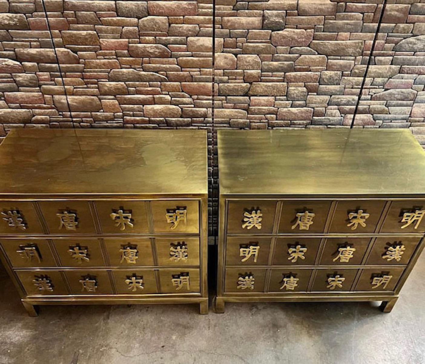 Pair of dynasty brass chest of drawers by Mastercraft. The chest includes pulls designed with Chinese characters which represent the four dynasties. Each dresser features three drawers and is in good overall vintage condition. There is some wear on
