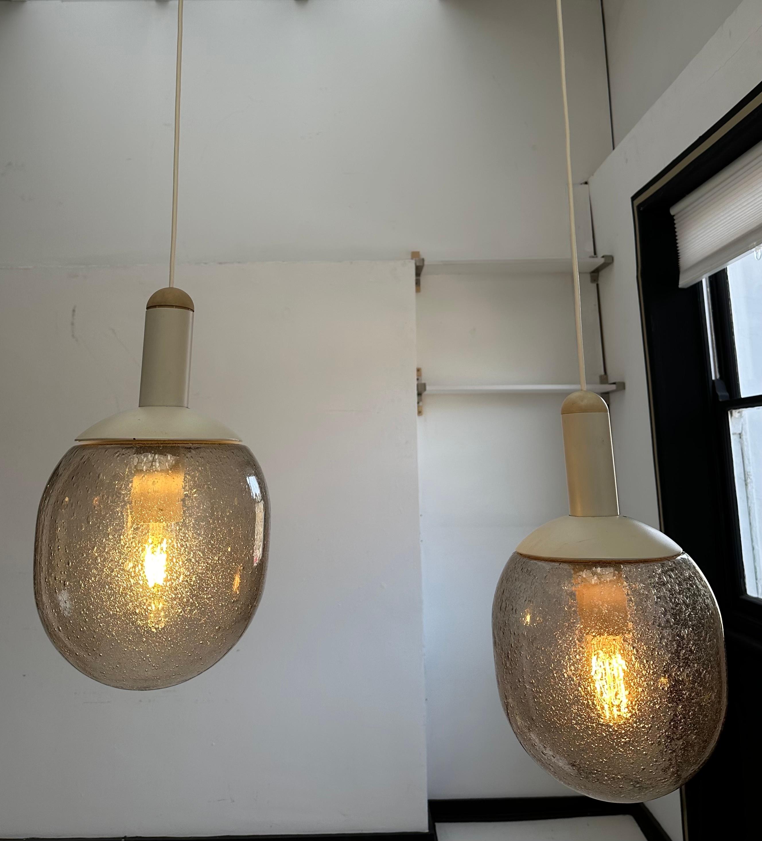 An unusual pair of 1970s German Glashütte Limburg pendant hanging ceiling lights with heavy smoked thick bubbled lozenge-shaped glass shades.  The shade is suspended from a metal white-coated bulb-holder with a vertical cyclinder above concealing