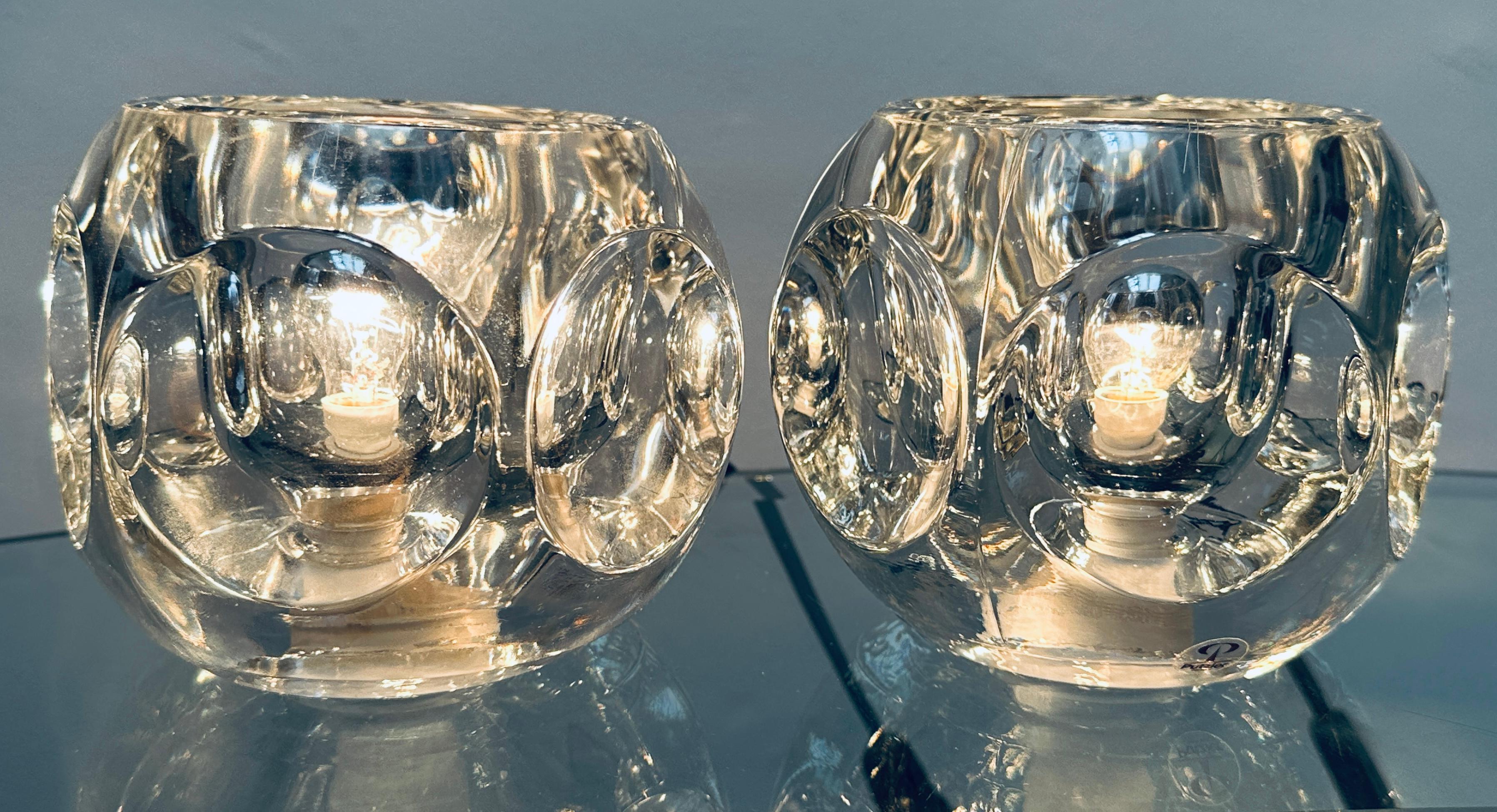 Pair of 1970s German Peill and Putzler round clear glass table lights with six concave indentations around the outside which magnify and reflect the light beautifully casting shadows around it and on the wall. An on/off switch is fitted onto their