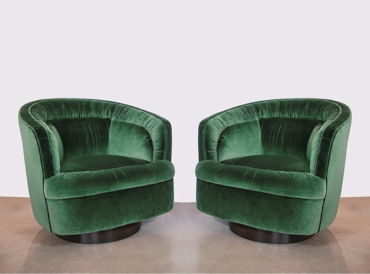 Stunning pair of ultra Luxe and comfortable swivel chairs in the style of Milo Baughman. Chairs are freshly upholstered in a green velvet, featuring a ruched tufting or pleated back resting on dark brown wooden bases, adds visual interest to the