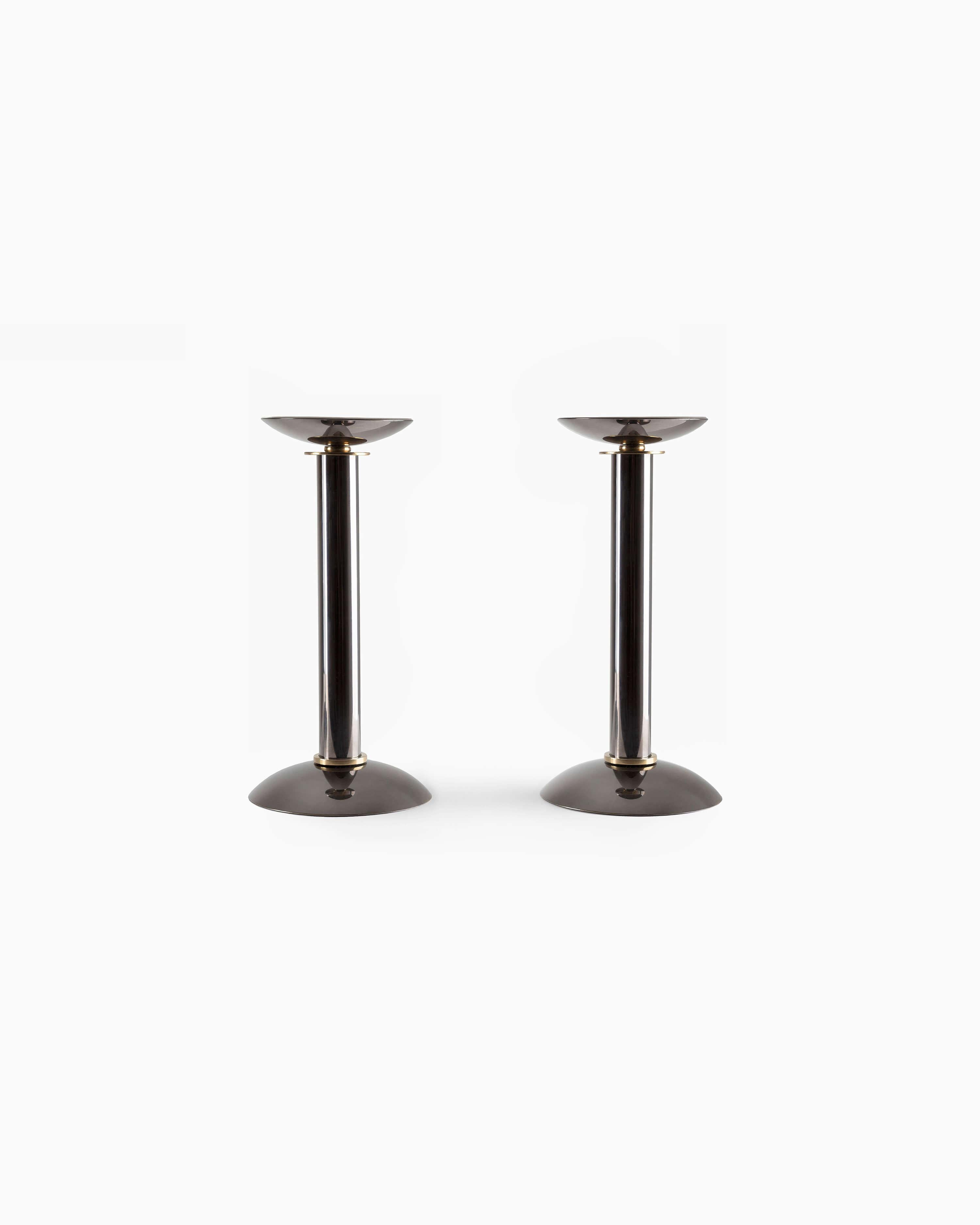This pair of candleholders in gunmetal feature an ornately detailed brass stand, offering a perfect balance of both refinement and warmth to any table. Springer was a prevalent German-American designer who prioritized craftsmanship in his attention