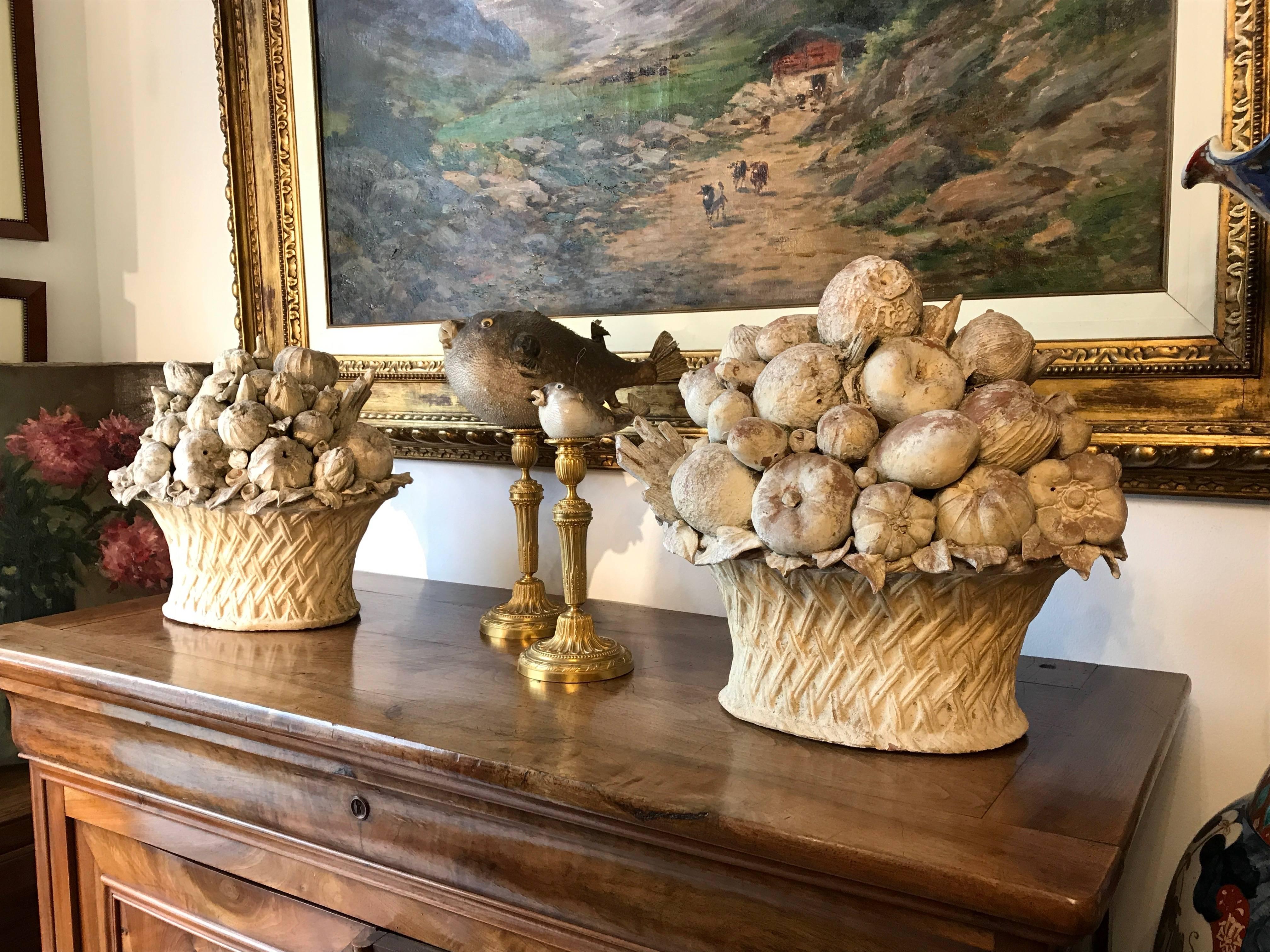 A charming pair of mid-20th century terracotta fruit and vegetable baskets, ideal as garden elements or indoors, as original centerpieces. These large terracotta sculptures, realized by the precious hands of a Tuscan artisan circa 1970s, are