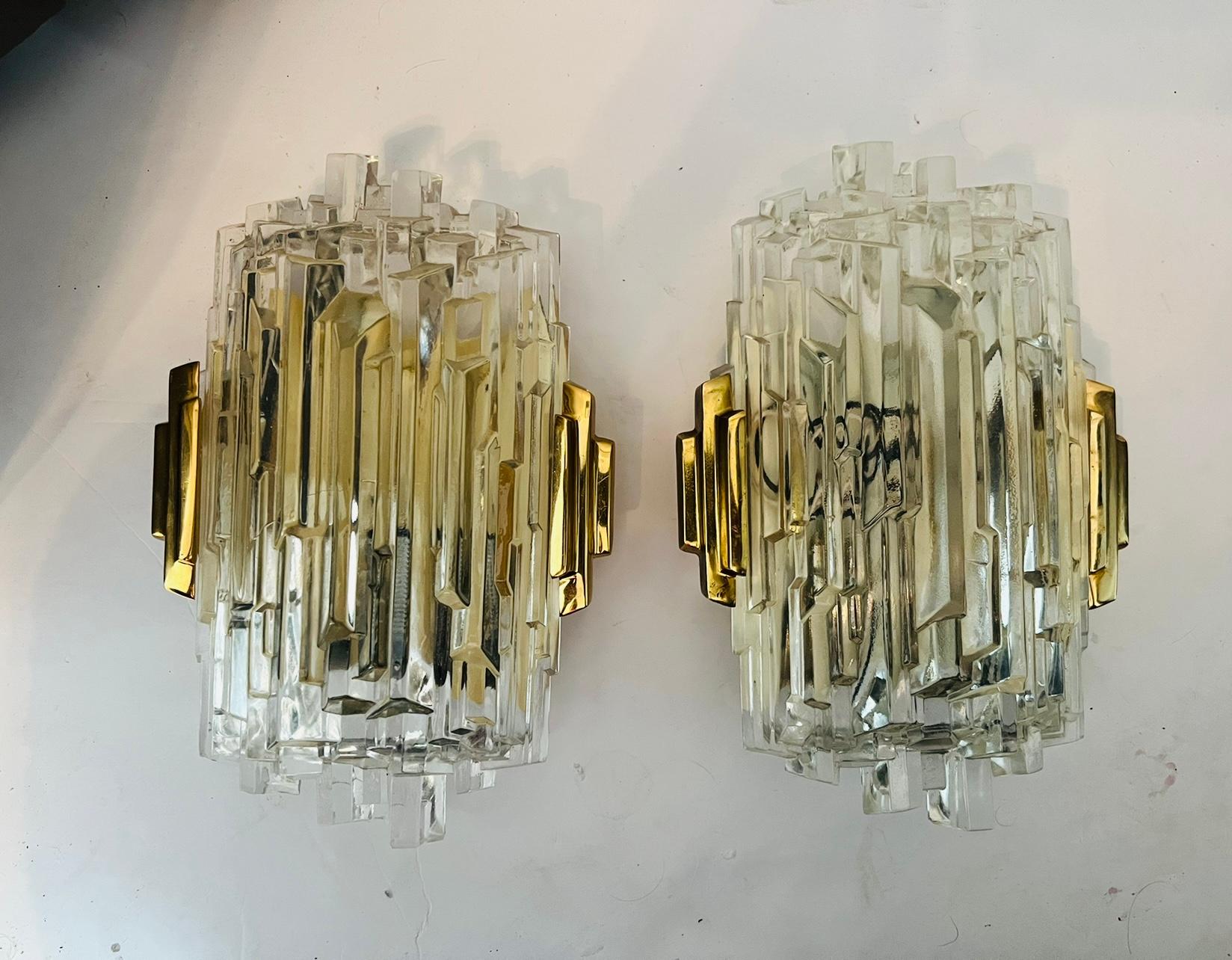 Pair of luxurious 1970s High Style wall lights composed of golden brass fittings and ice crystal glass shades. Newly rewired. Candelabra sockets.
