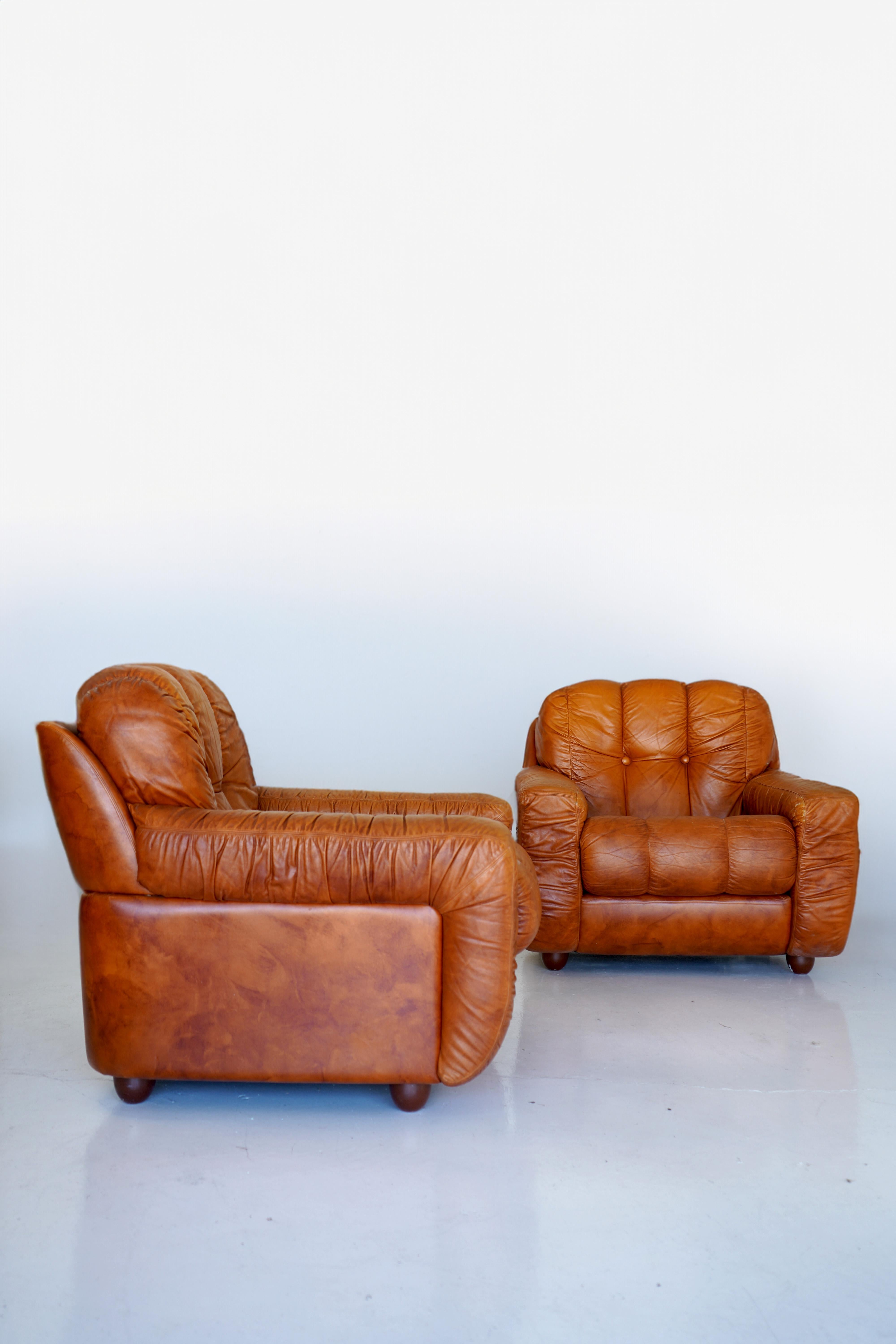 Classic 70s vibes on these channeled Italian leather armchairs with vinyl frame in the style of De Sede. Matching sofa also available.

Wear and slight losses to upper edge of backside but otherwise in good condition.