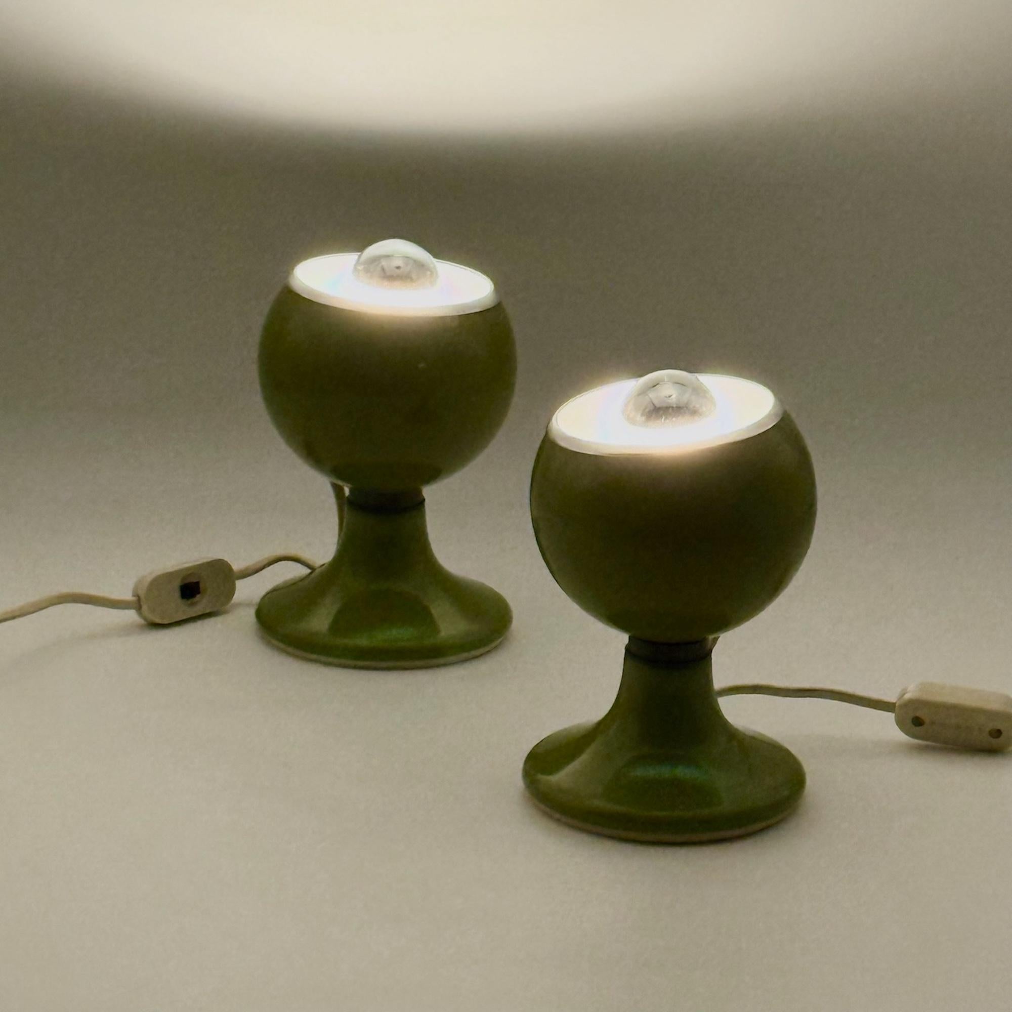 Rare paire de lampes Eyeball des années 1970 fabriquées par Luci en Italie, illustrant l'expérimentation ludique de l'ère du design spatial. Chaque lampe est dotée d'un abat-jour en métal laqué vert brillant monté sur un socle pivotant magnétique,