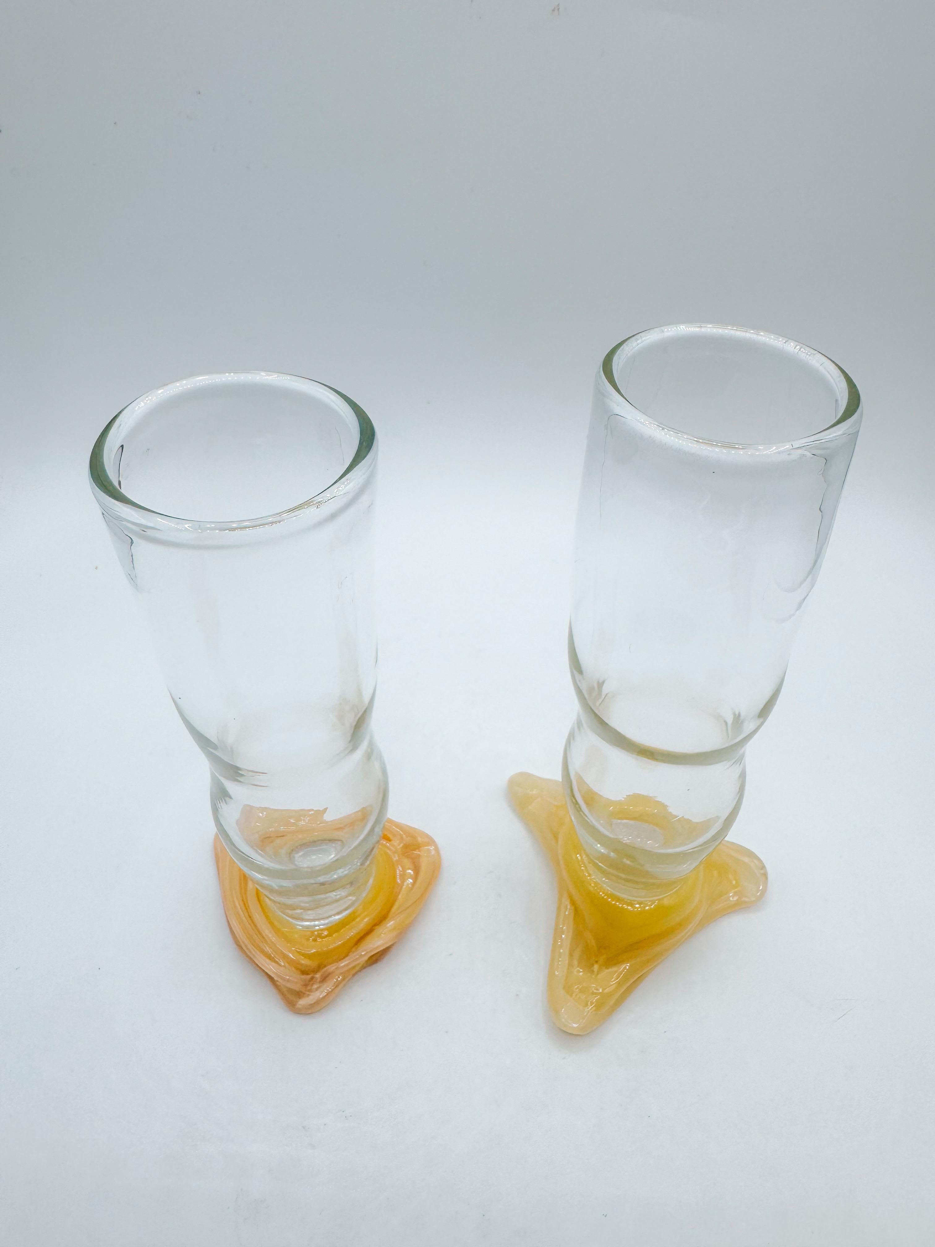 Juguetón y escultural, este par de vasos artísticos mexicanos hechos a mano en la década de 1970 muestra el arte expresivo del soplado de vidrio en taller. Cada vaso presenta un curvilíneo cuenco transparente de forma orgánica que se asienta sobre