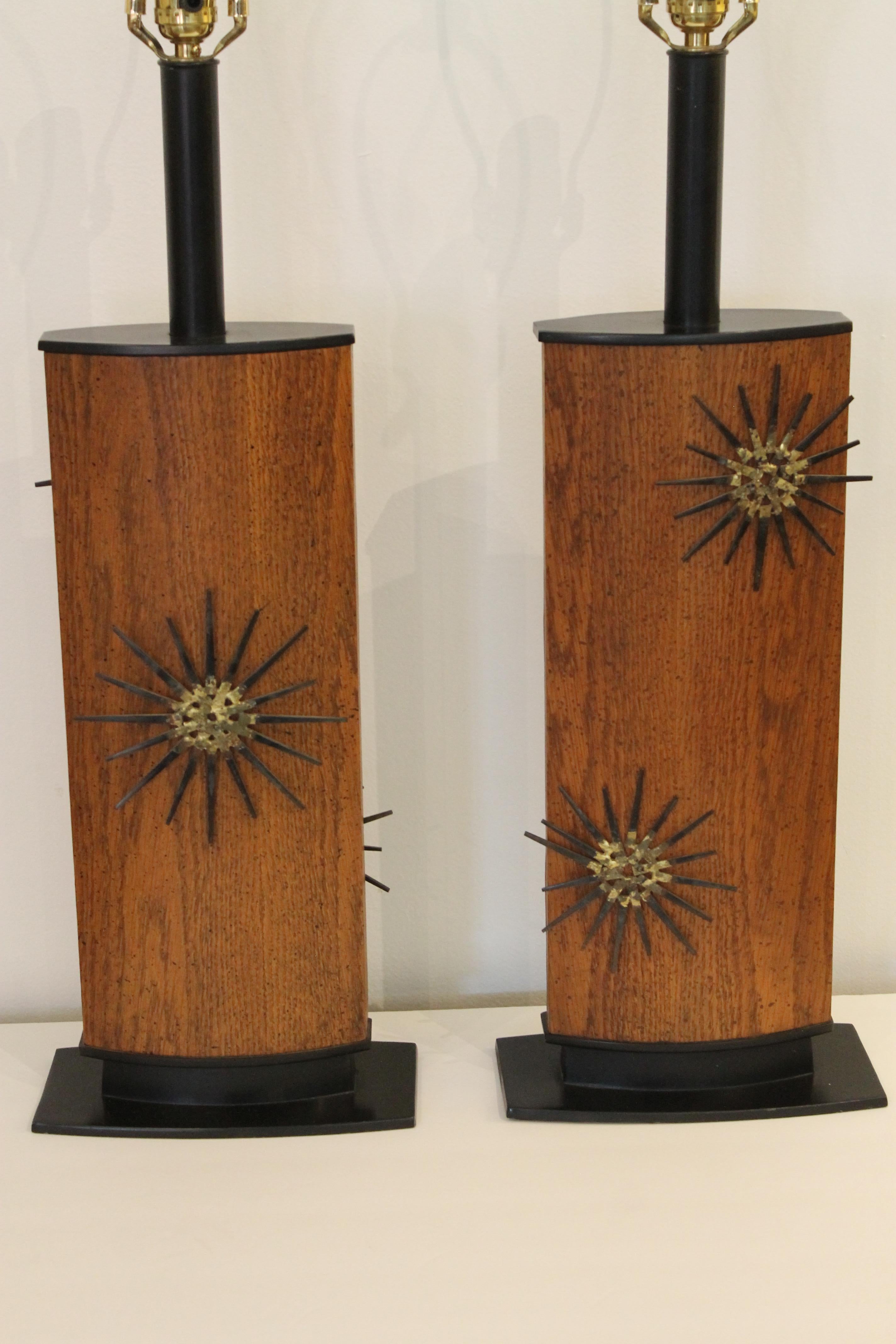 A matched pair of painted steel and wood table lamps with nail art sunburst elements front and back. Interesting feature here is that the lamps are reversible. The central wood portion rotates on the base so that you have the option to show the side