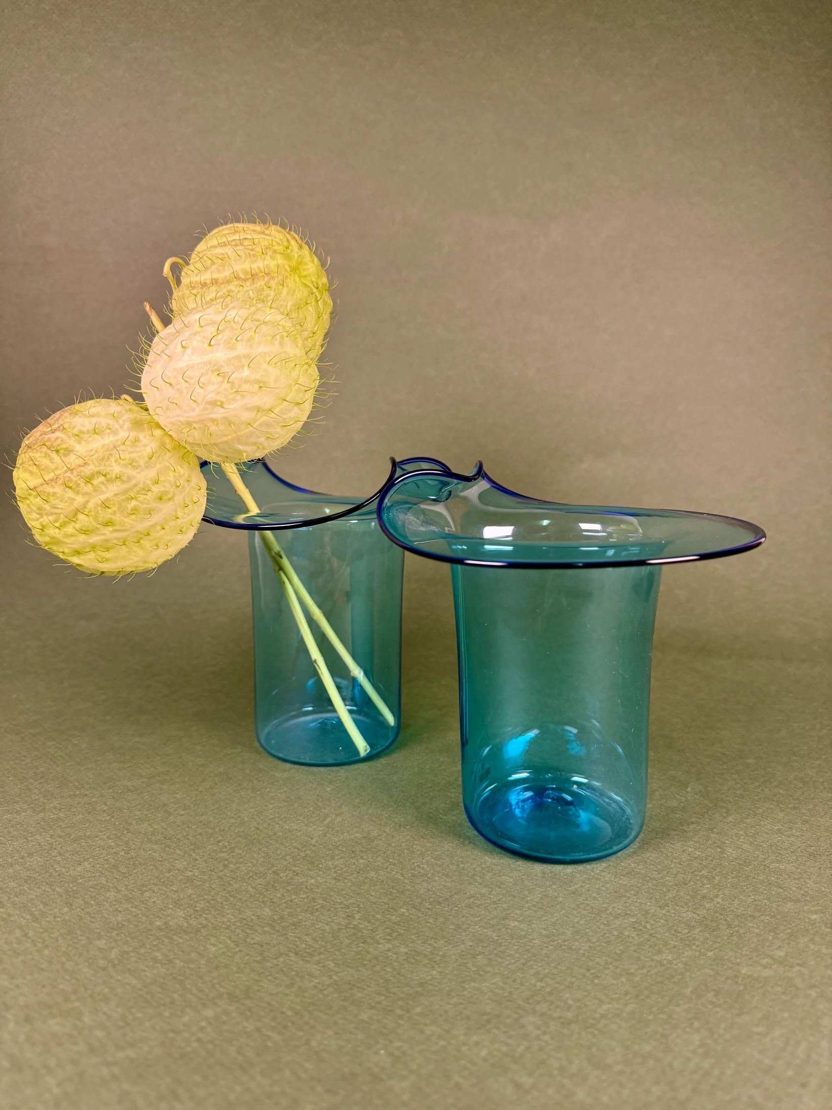 Une élégante paire de vases en verre de Murano datant des années 1970, fabriqués à la main dans un verre translucide bleu aqua qui capture et reflète la lumière avec une fluidité remarquable. Chaque vase est doté d'un rebord aux contours doux et aux