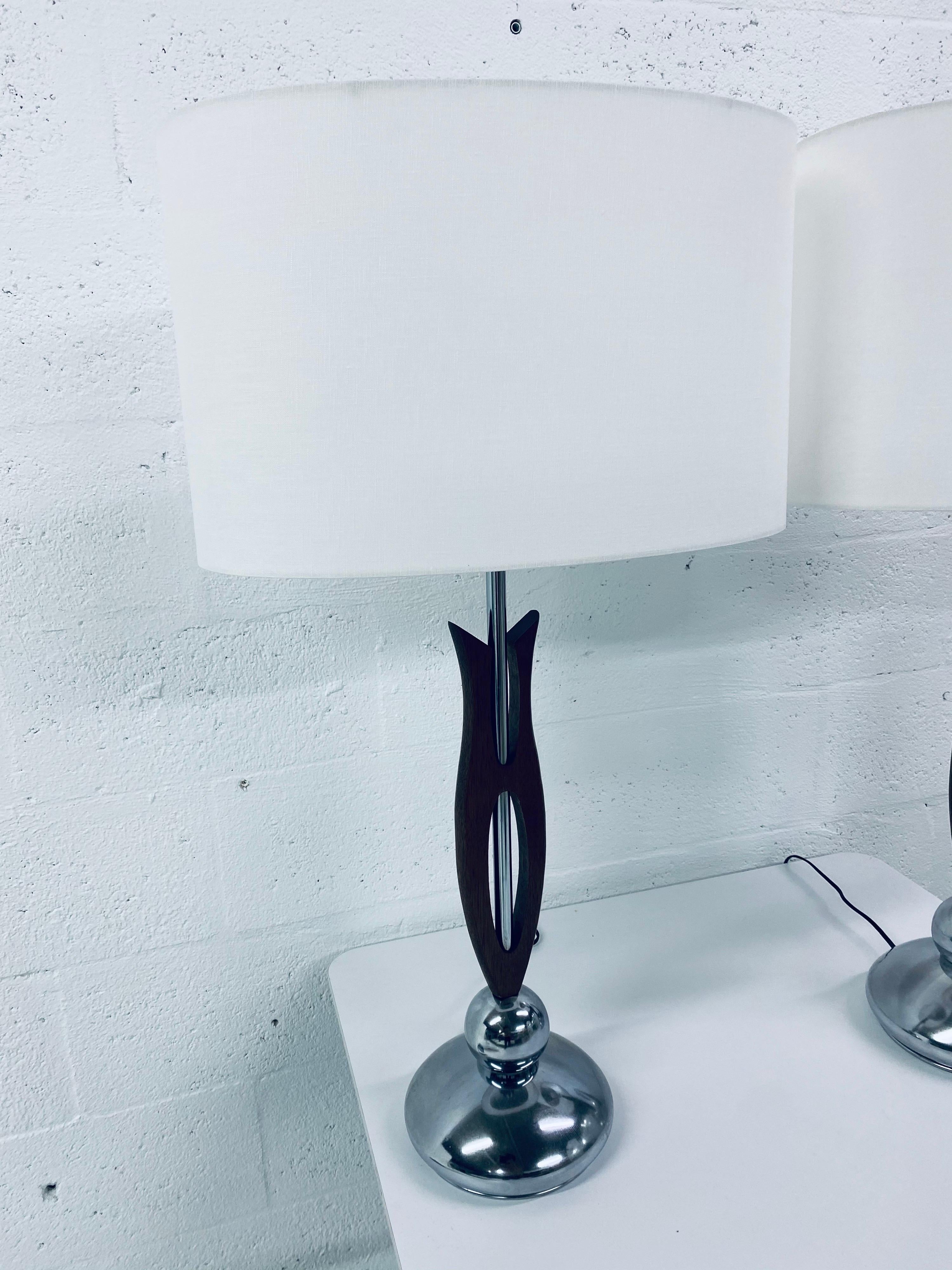 Two desk or table lamps by Nova Lighting with chrome hardware and carved wood detailing. Bright white oval lampshades are new and made from 100% cotton linen.