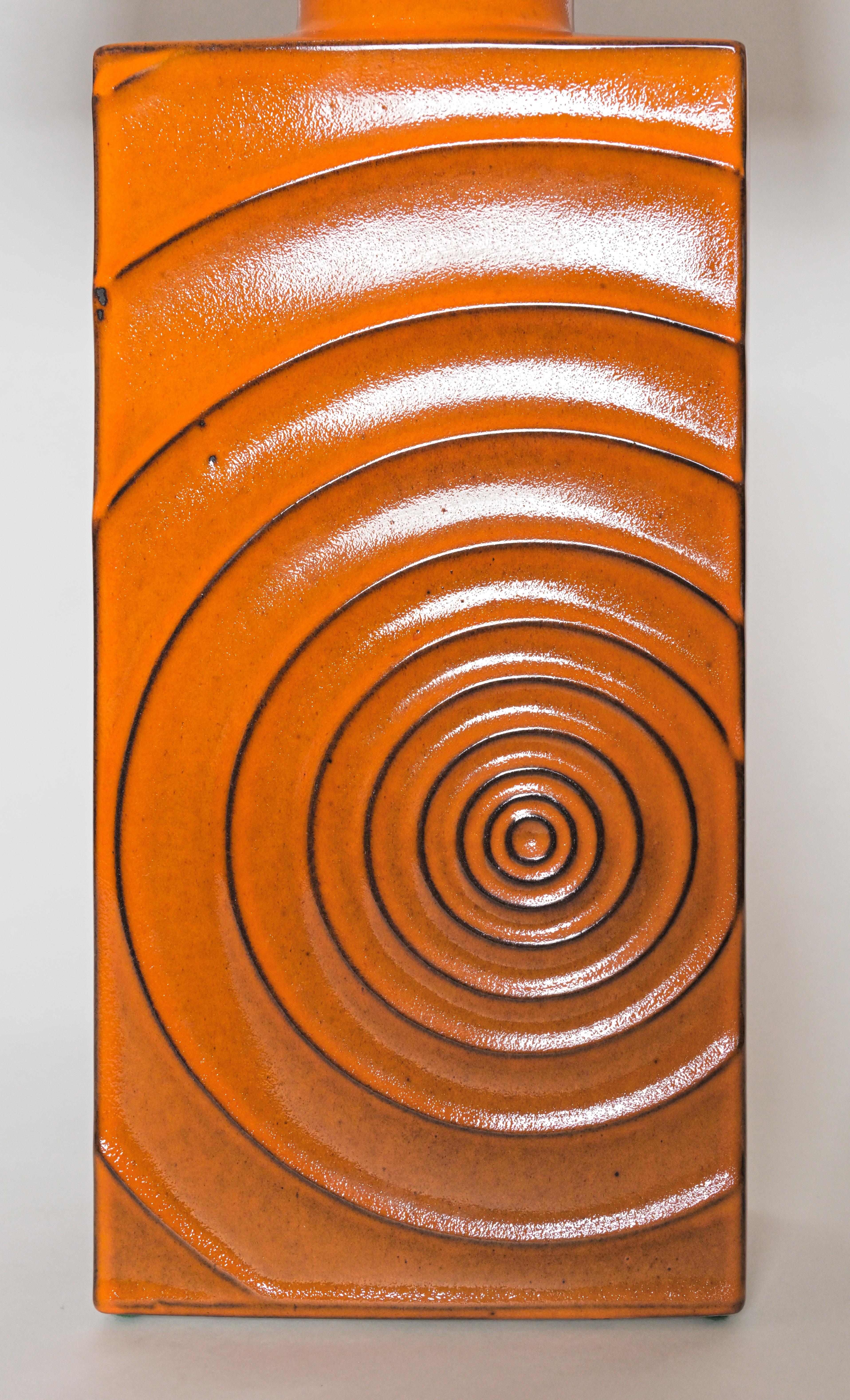 A pair of orange earthenware Modern table lamps having curved indentations of a spiral motifs along the front. circa 1970s. Newly wired. 

Adjustable shade height.