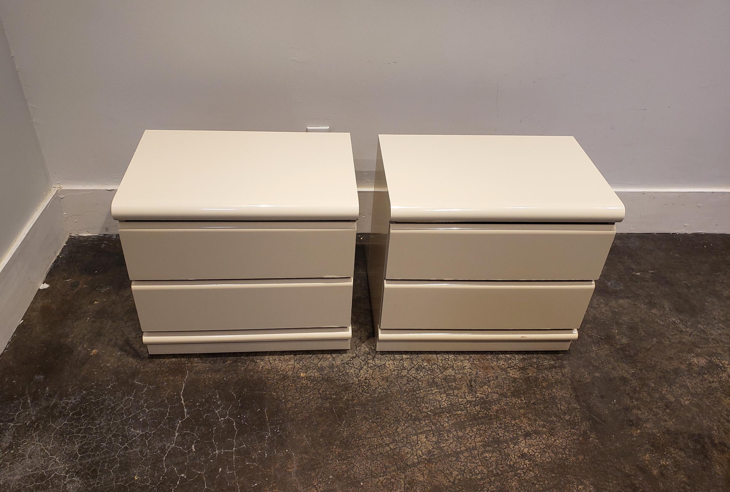 Pair of white lacquered two-drawer nightstands manufactured by Broyhill in the 1970s. Slick minimal design; white rounded fronts with brass/gold veneer accents.