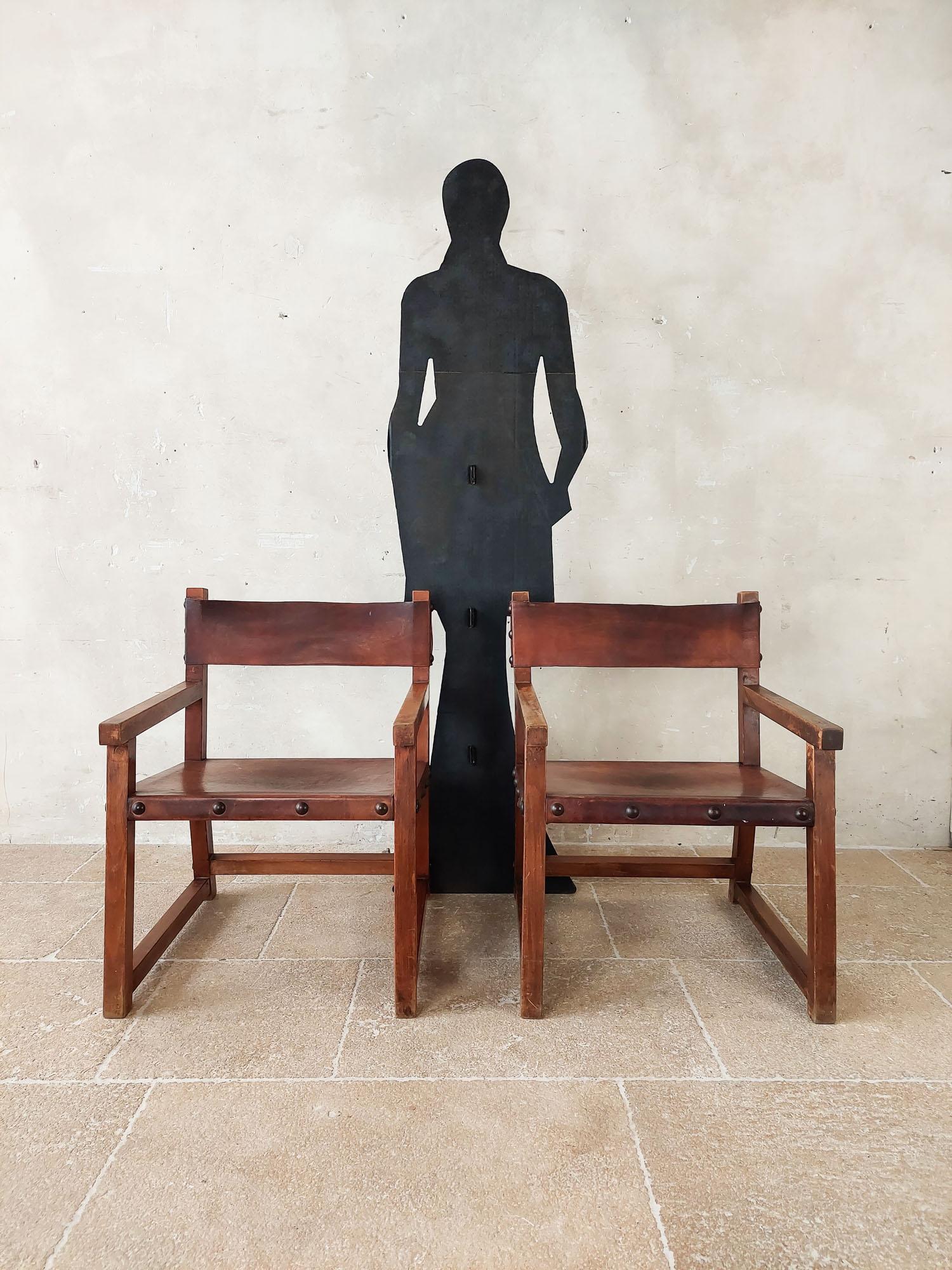 Paar spanische Vintage-Sessel aus Leder und Holz im Stil von BIOSCA, Spanien der 1970er Jahre. Diese robusten brutalistischen Loungesessel sind aus schönem Sattelleder gefertigt, das mit Eisennägeln mit dem Eichengestell verbunden ist. 
Der Preis