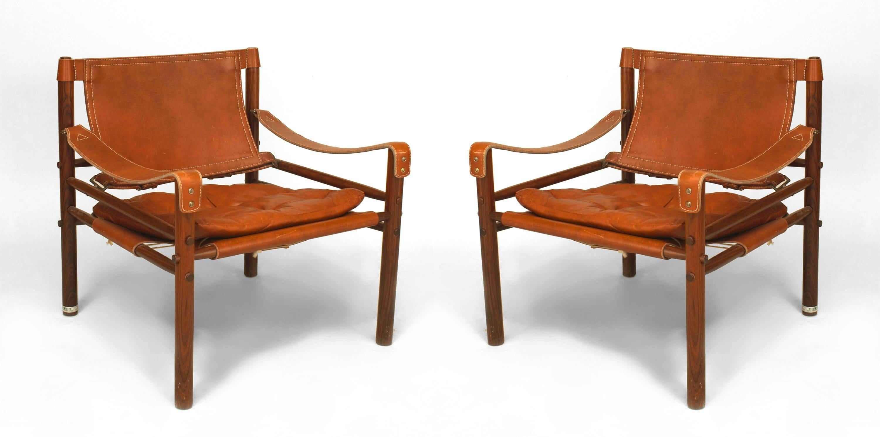 Pair of 1970's Swedish rosewood armchairs with brown leather arm rests, backs, and seats with tufted cushions and brass buckles. Labeled 