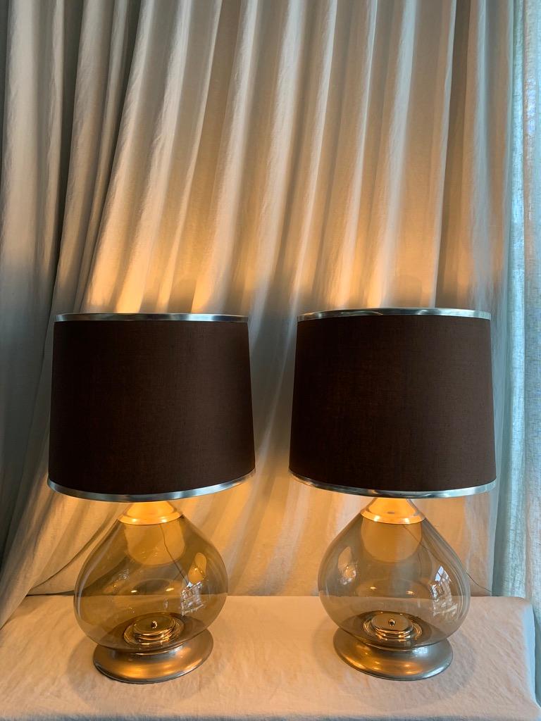 Vintage pair of 1970s French large table lamps in mouth blown smoke colored glass on mounted metal base and metal top. The original hand made lamp shades in brown colored canvas. The lamps have 3 light sources each. 
