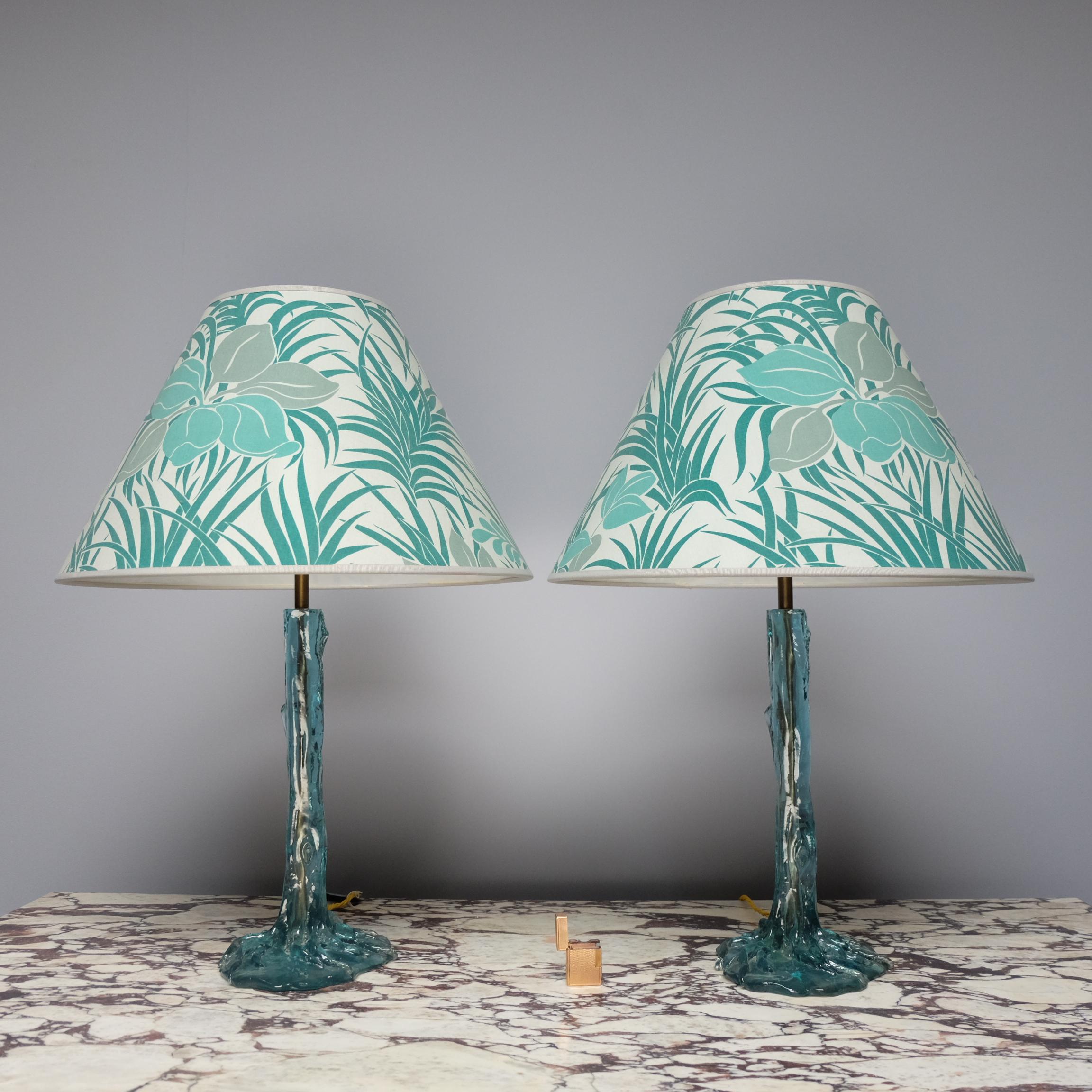 Pair of 1970s turquoise resin table lamps formed in the shape of a tree and roots. A brass rod runs through their centres where the wires are hidden. Their original conical shades feature turquoise flowers and palm leaves against a white background.