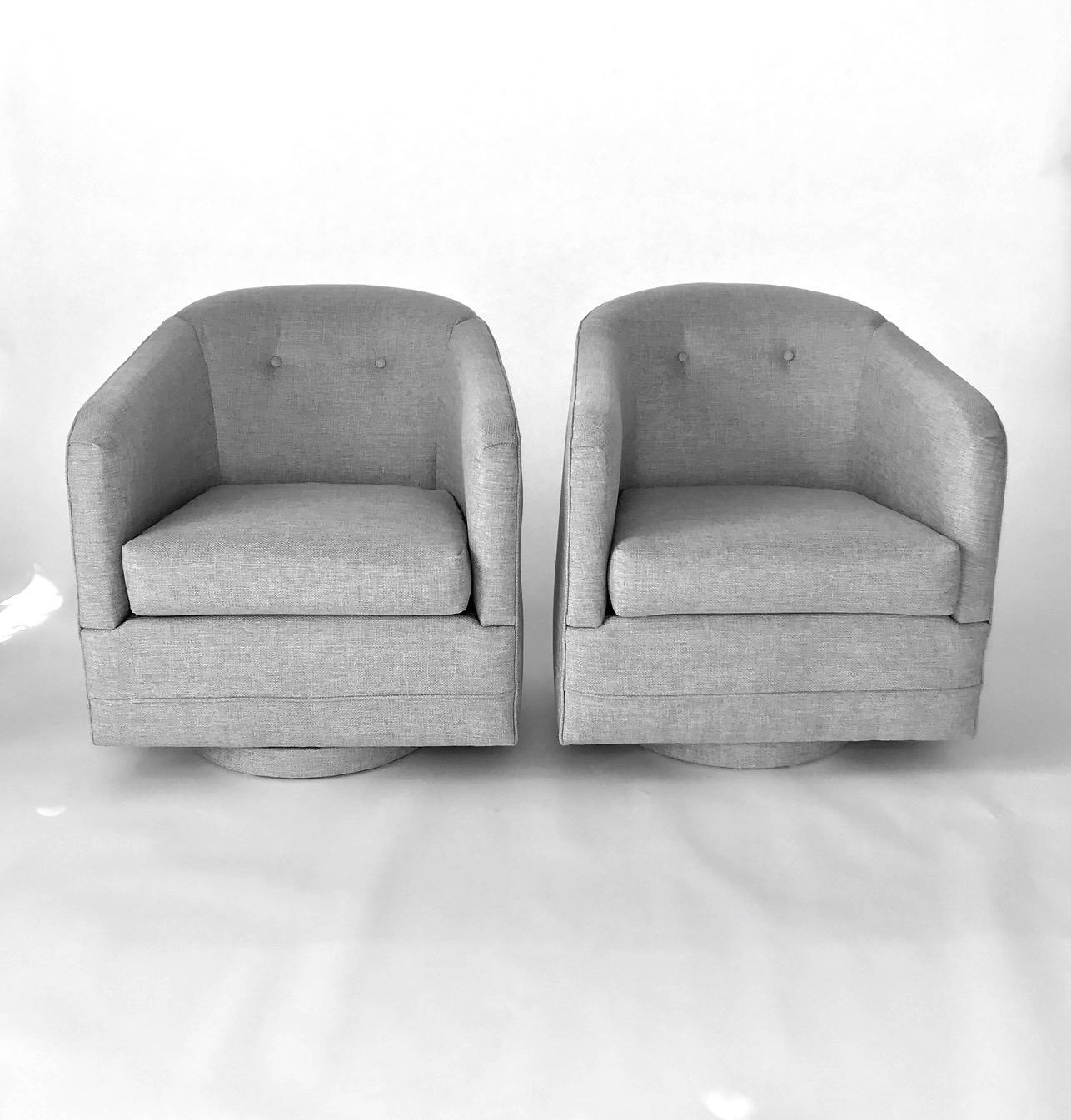 Pair of Mid-Century Modern lounge chairs in elegant basket woven fabric in hues of grey and taupe. Chairs feature upholstered bases with full swivel design. Barrel back forms with rounded edges and button back details. Gorgeous from every angle.