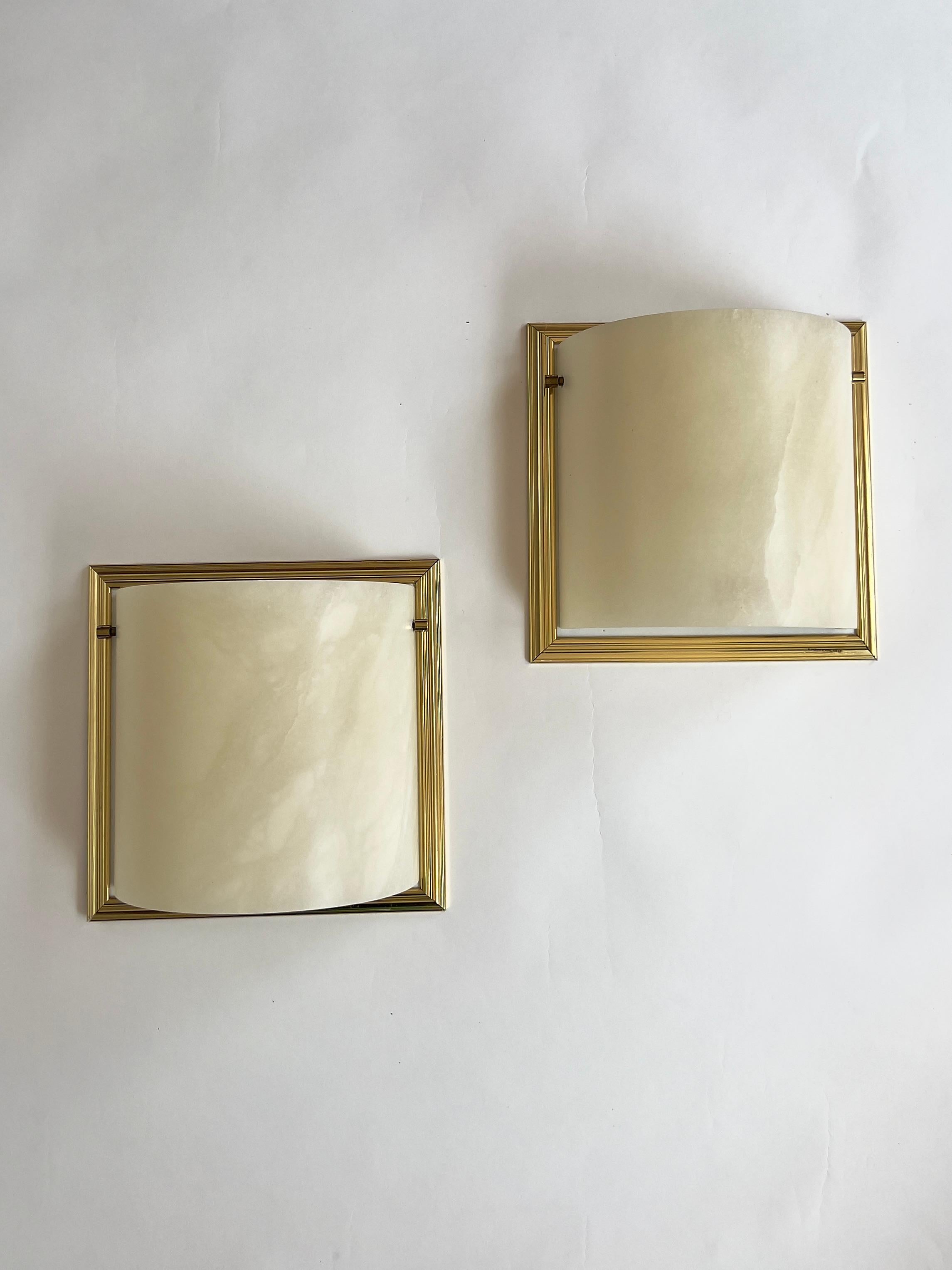 An elegant pair of vintage 1980s demilune wall sconces by Lightolier. Curved alabaster shades are mounted in refined, reeded brass frames. The stone’s natural veining allows for a warm ambient glow when lit. Signed “Lightolier” on the frame.
