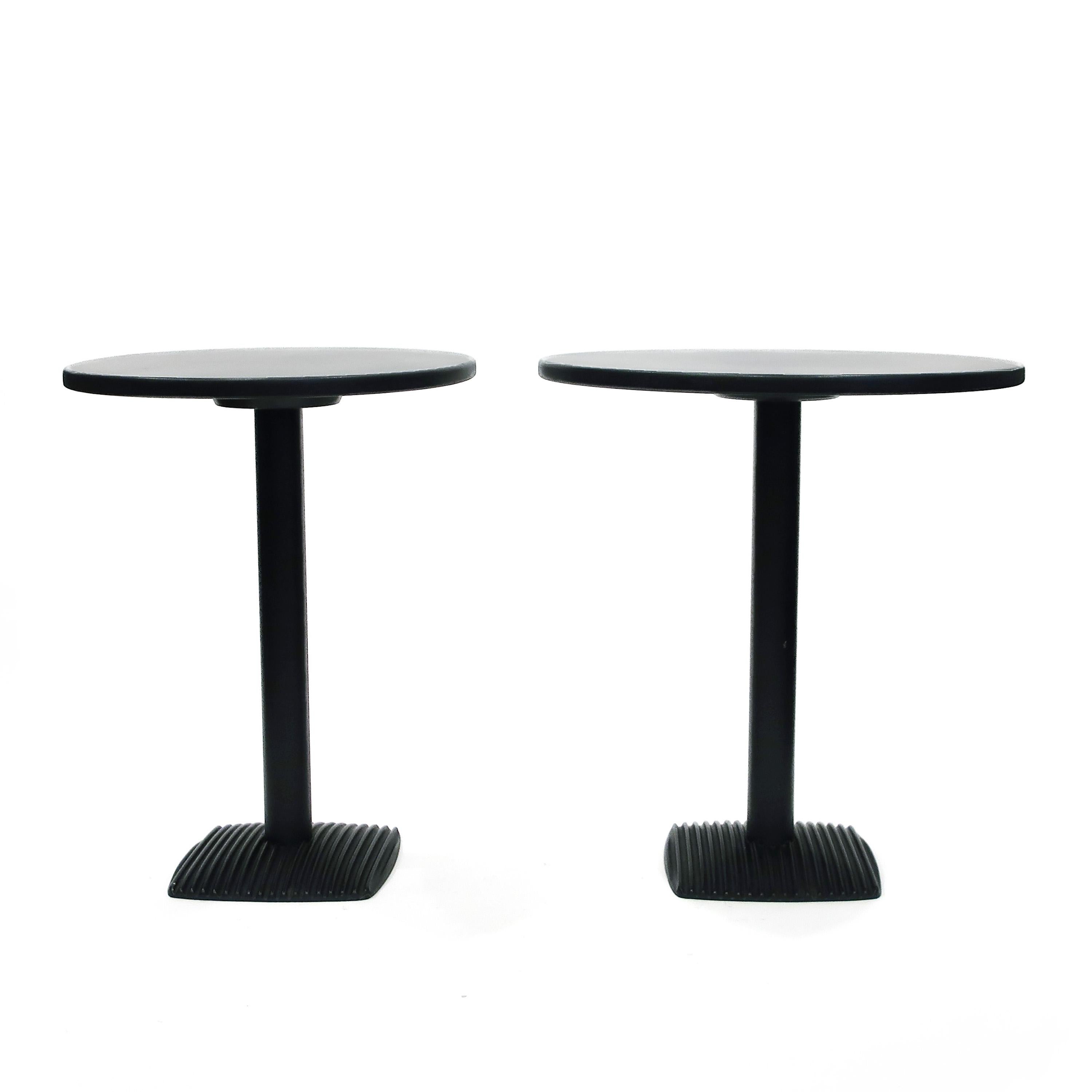 A pair of simply designed side or drinks tables with a black painted iron base and black laminate over wood tops. Bases are matching while one top is round and one is oval. Functional and beautiful in their Minimalism. Likely Italian from the