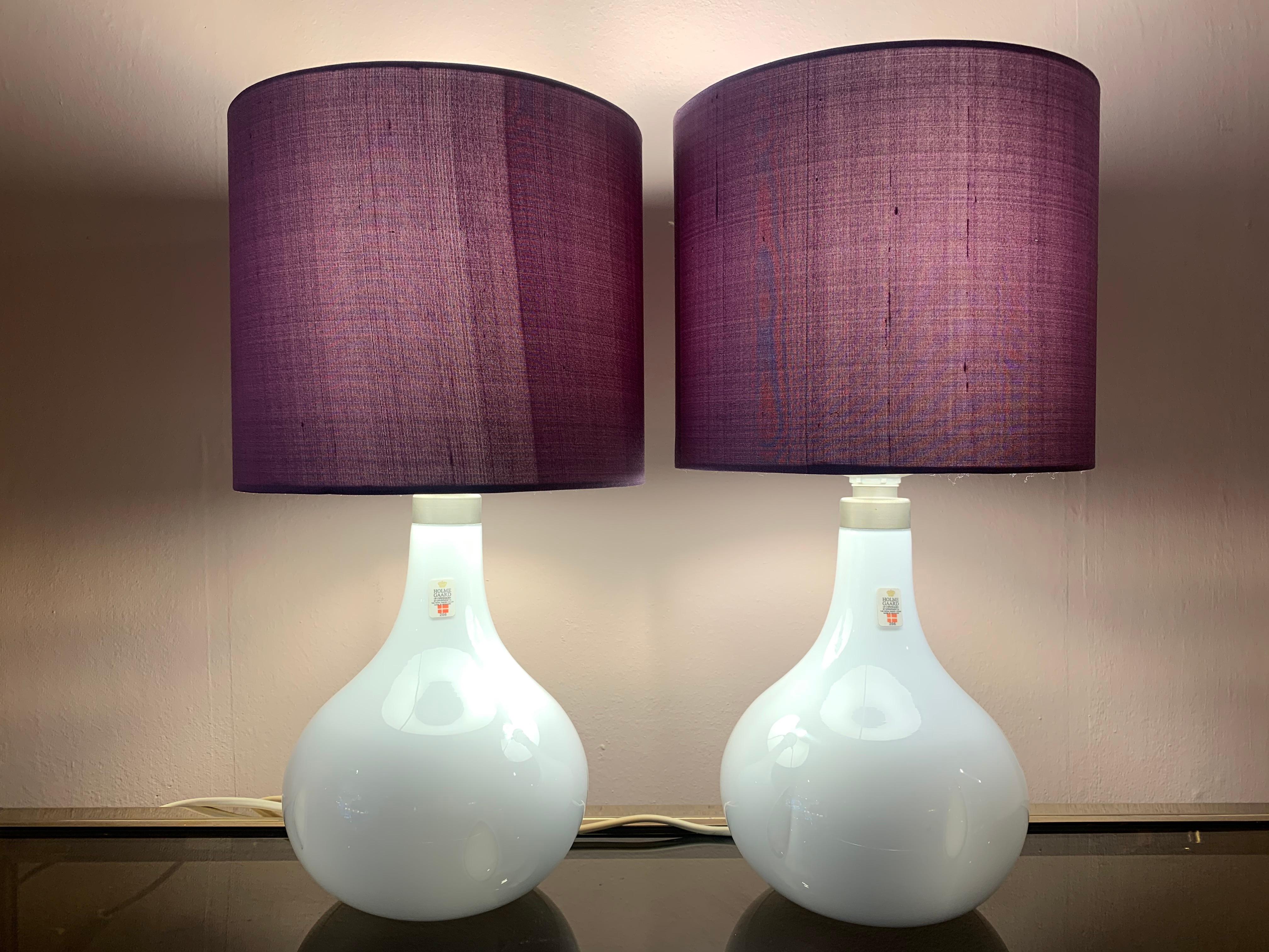 Pair of small Danish hand blown milky white gloss glass table lamps with encased feature clear teardrop inclusions. Manufactured by Holmegaard from their Helios Bordelampe range. Designed by Peter Svarrer.

Original label states: HOLMEGAARD. Type: