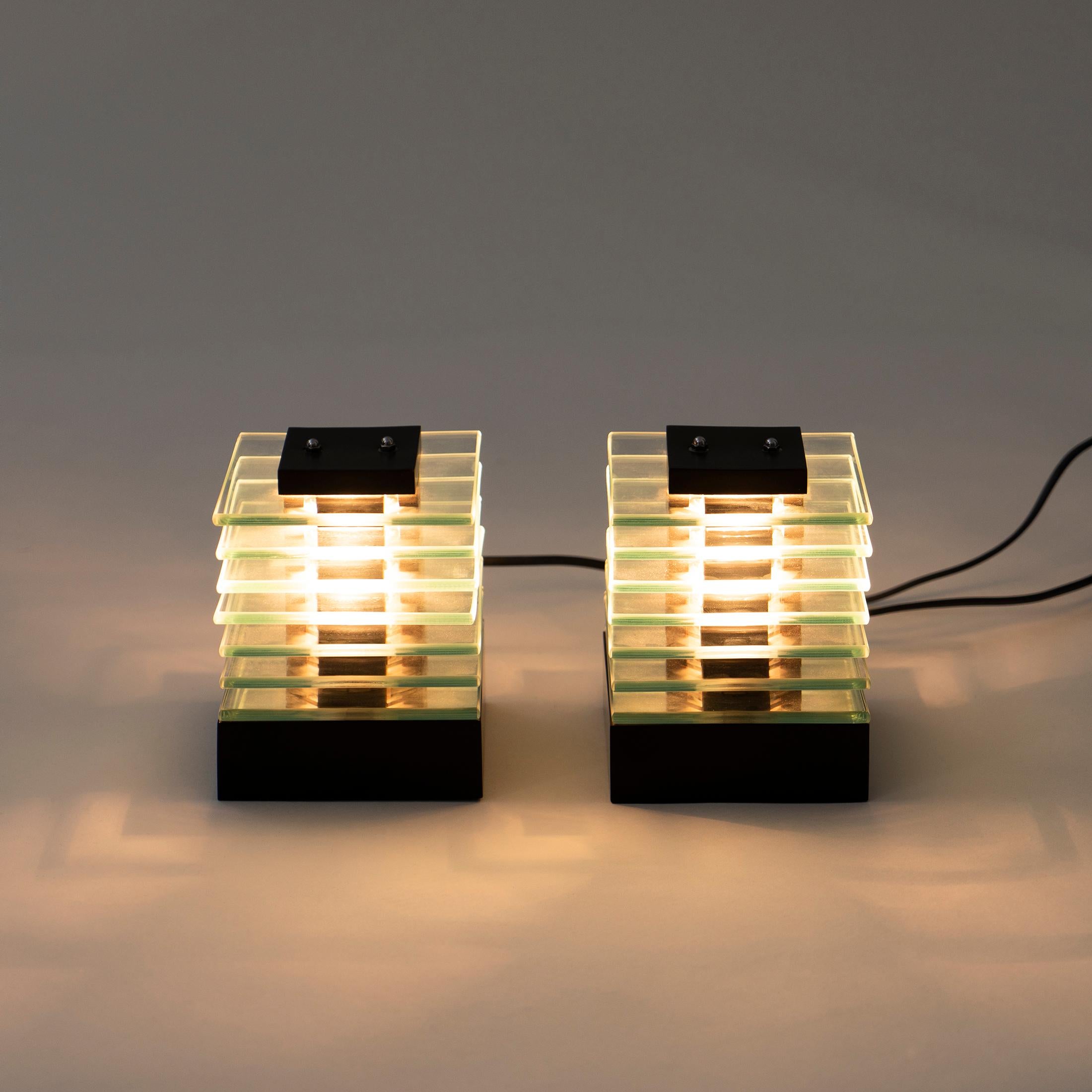 Cool 1980s English pair of cube lights. Each light consists of seven tiers of glass layer on a dark wooden base to create a cube. Central dark column detail runs down the centre. Light reflects through the cube creating an interesting and warm