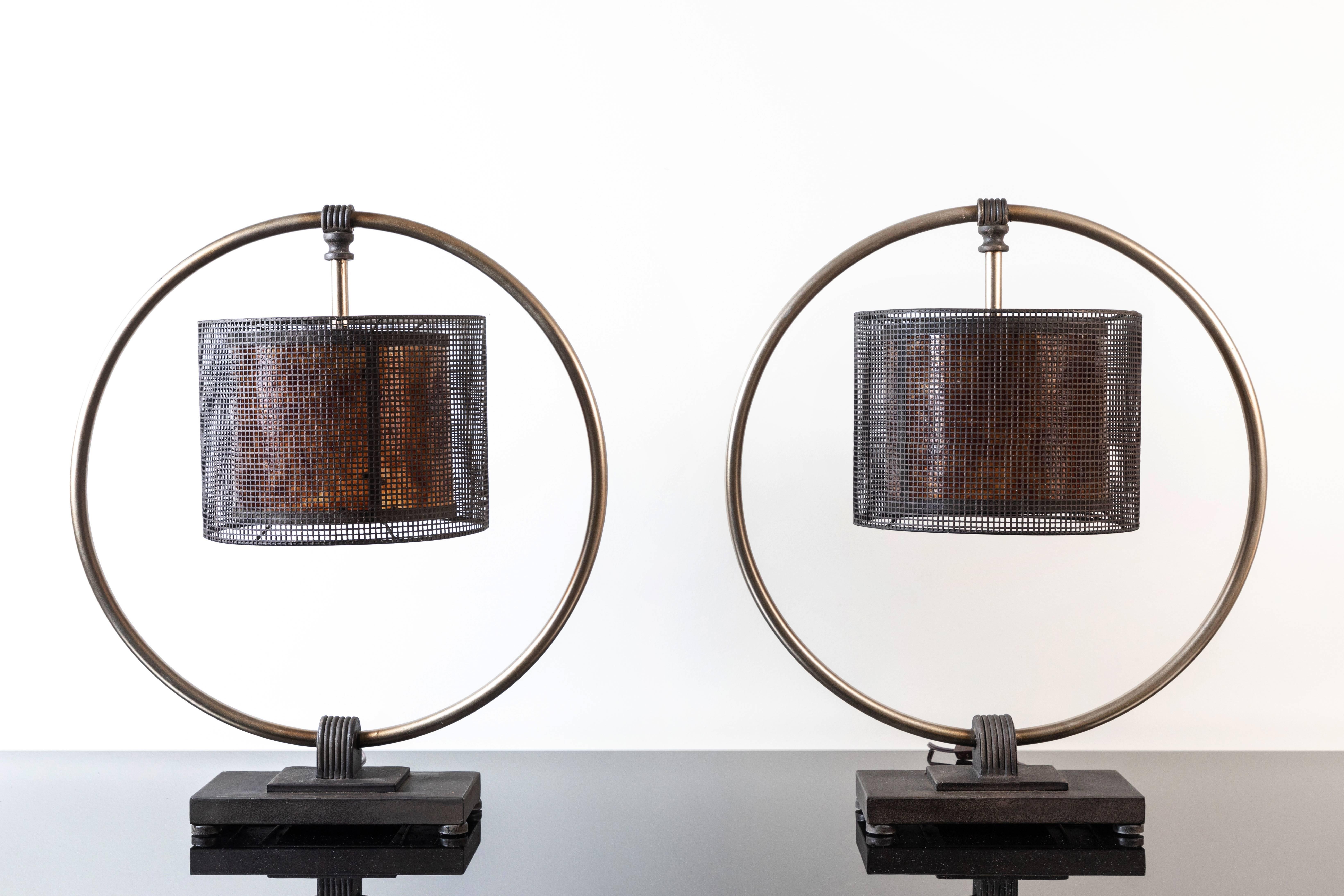 Unusual pair of metal lamps attributed to Aldo Tura, 1980s. Industrial with a Memphis vibe, the lamps have a round metal ring attached to a metal base with a metal mesh shade suspended from the upper part of the ring. Very cool.