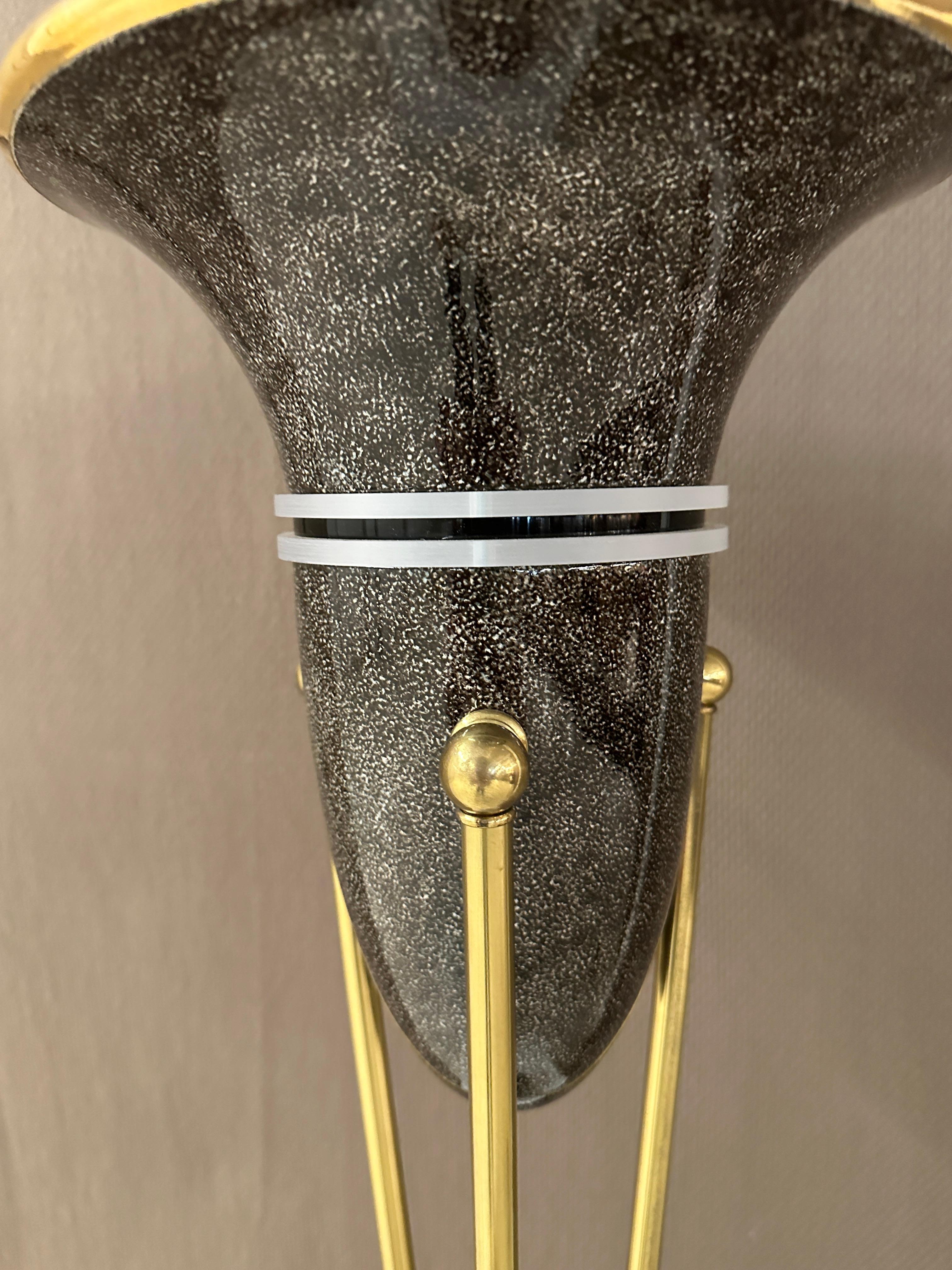Alan Peterson, a ceramist and designer, crafted this dramatic pair of torchieres. Made of black-flecked grey lacquer ceramic, these pieces feature inverted conical domes, iconic of 1980s style. Supported by three sleek brass arms, the torchieres
