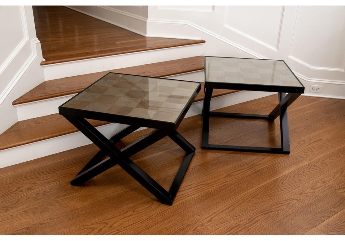 Fine quality decorative square end tables with gilt grid patterned tops comprised of alternating gold and silver squares under glass. Mounted on black painted X-form bases. The pair may be used side by side as a cocktail table.
Measures: 24 x 24