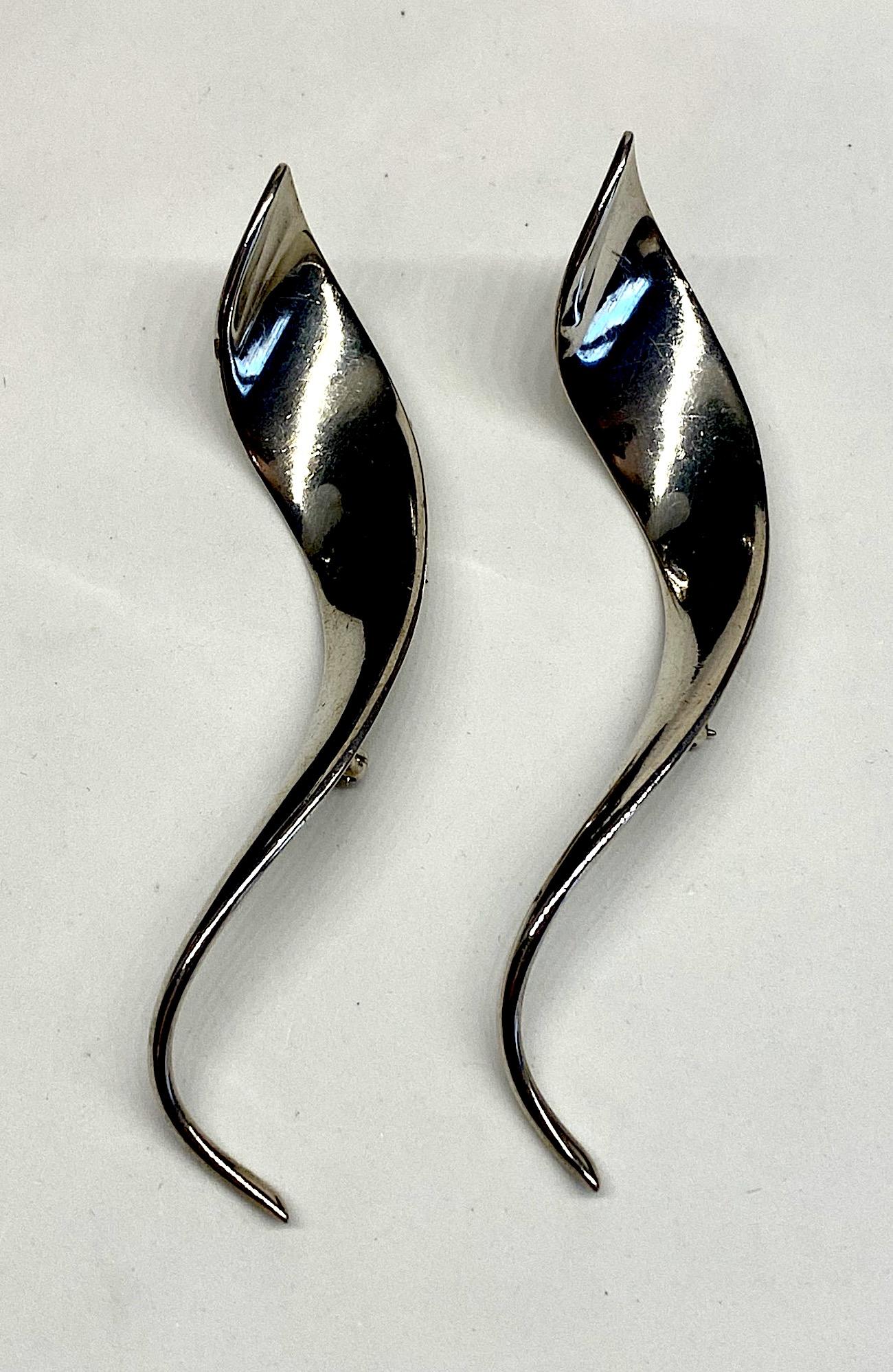 A lovely matched pair of sterling silver freeform abstract spiral brooches. Each brooch is a three dimensional spiral design and measures .75 of an inch at the top and tapers down to a point. They are 4.25 inches long and 1 inch deep. The backs are