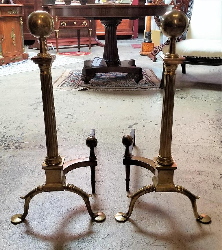 PRESENTING A GORGEOUS Pair of Early 19C Philadelphia Brass Andirons with Roman Columns and Ball Finials.

Made in Philadelphia, circa 1800 -10, during the Federal Period.

Made of solid brass, the Andirons each sit on 2 bun feet with curved, flowing
