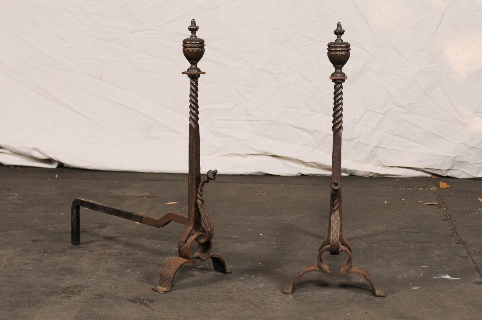 Pair of 19th-20th century iron andirons with partial twist columns and urn shaped finials.