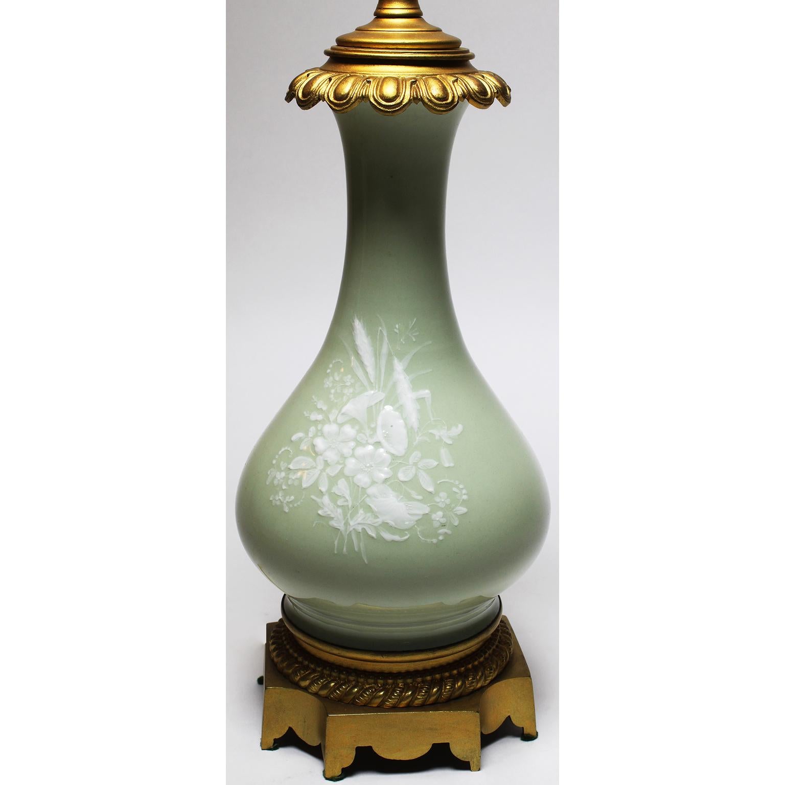 A fine pair of French 19th-20th century Pâte-sur-Pâte Porcelain and gilt-bronze mounted ovoid-shaped table lamps with a white low-relief floral design carved in slip and applied to a contrasting body over the blue-green porcelain, Paris, circa