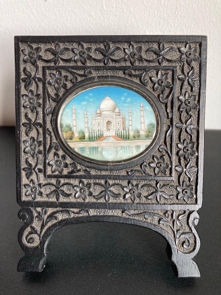 Miniature oval paintings of both the exterior and interior views of the Taj Mahal, in hand carved ebony frames with brass stands. These beautifully painted miniatures show great detail in such a small space. The interior view with gilt highlights is