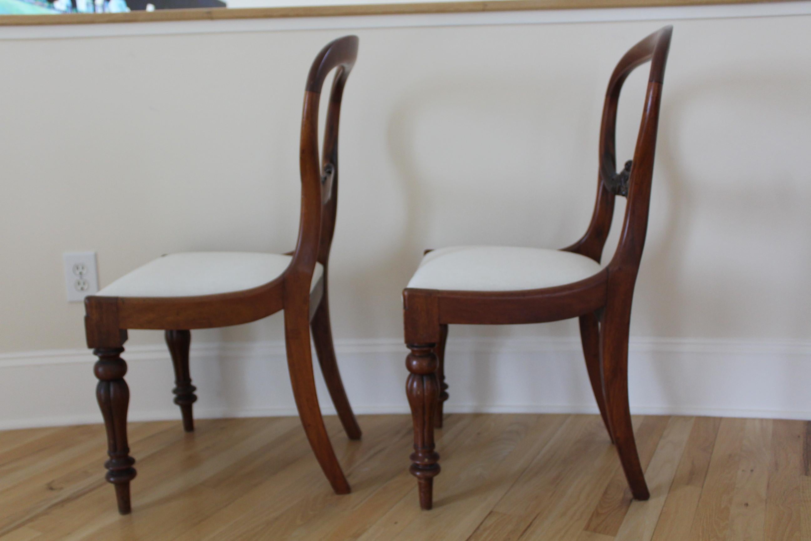 Pair of 19th century. Balloon back mahogany side chairs in the regency St. This pair is carved out of solid mahogany with turned front legs and saber back legs. Seats are upholstered and removable for re upholstering.