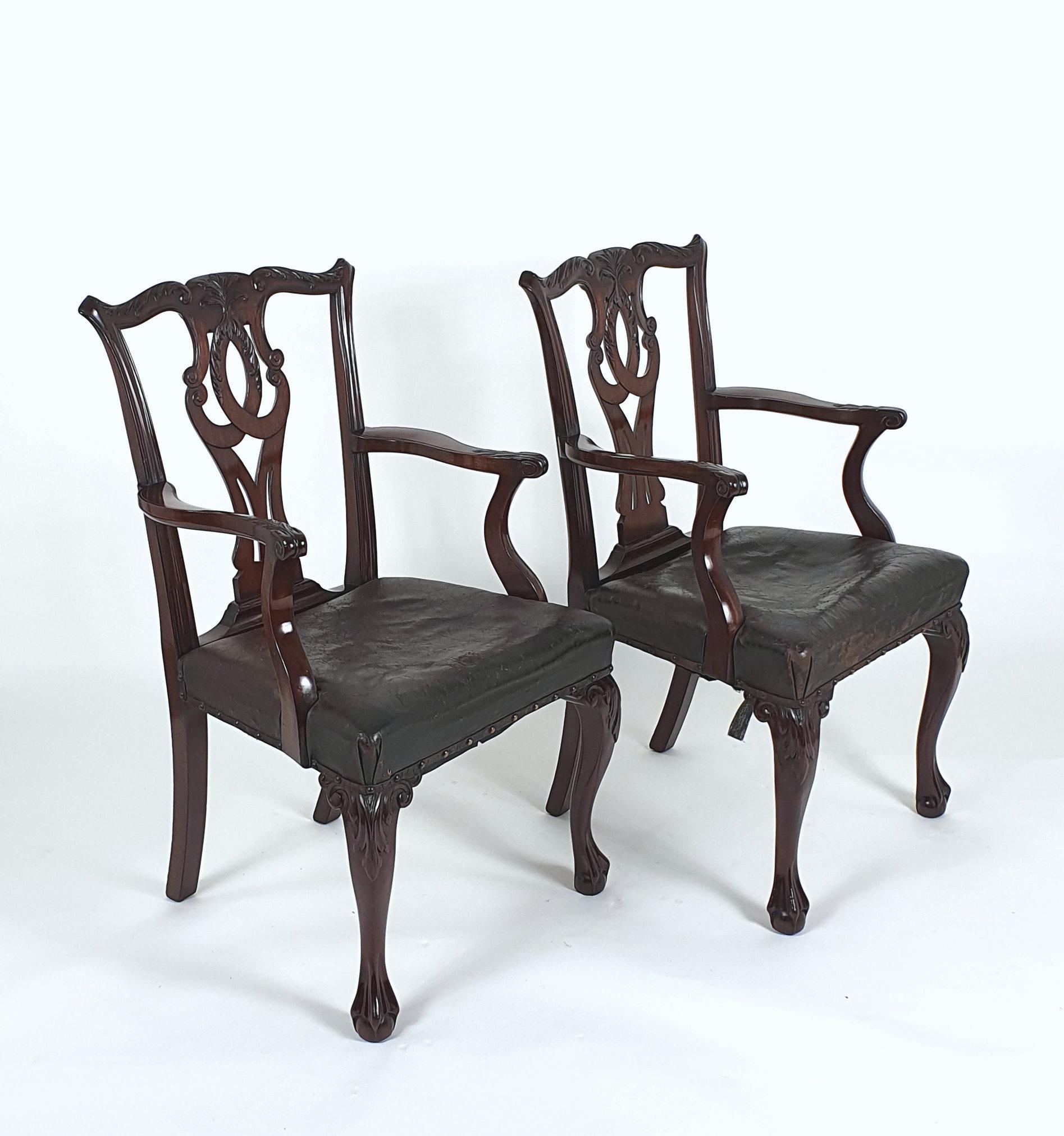 This pair of extremely handsome and splendid 19th century Chippendale designed elbow chairs are of a Chippendale design with cabriole leg supports and ball and claw feet. The seats have a distressed dark brown leather hide, that are well worn but