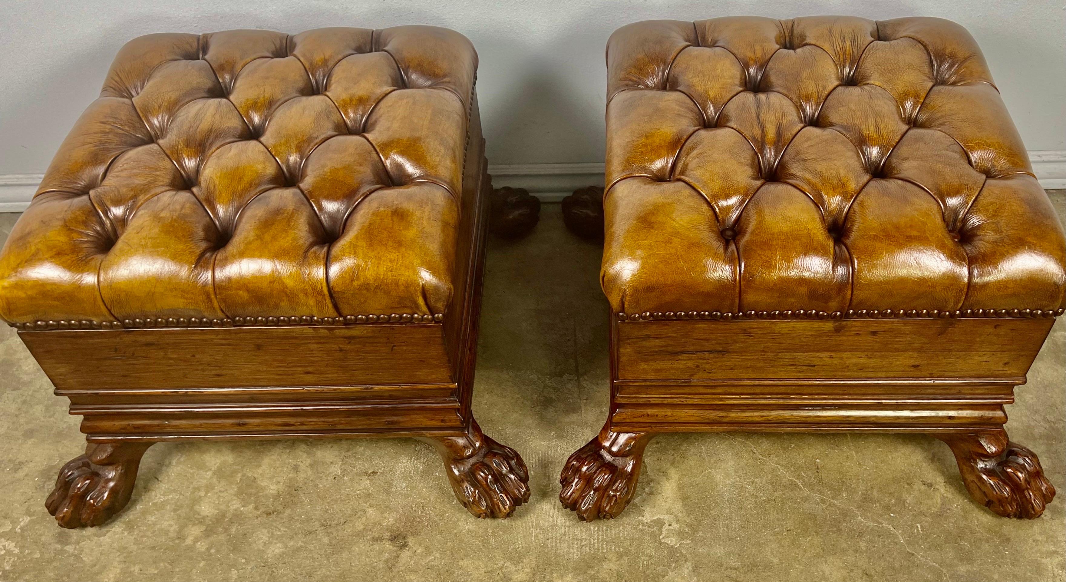 Pair of 19th century English Regency style foot stools standing on paw carved wood feet. The benches are upholstered in tufted leather with nailhead trim detail.