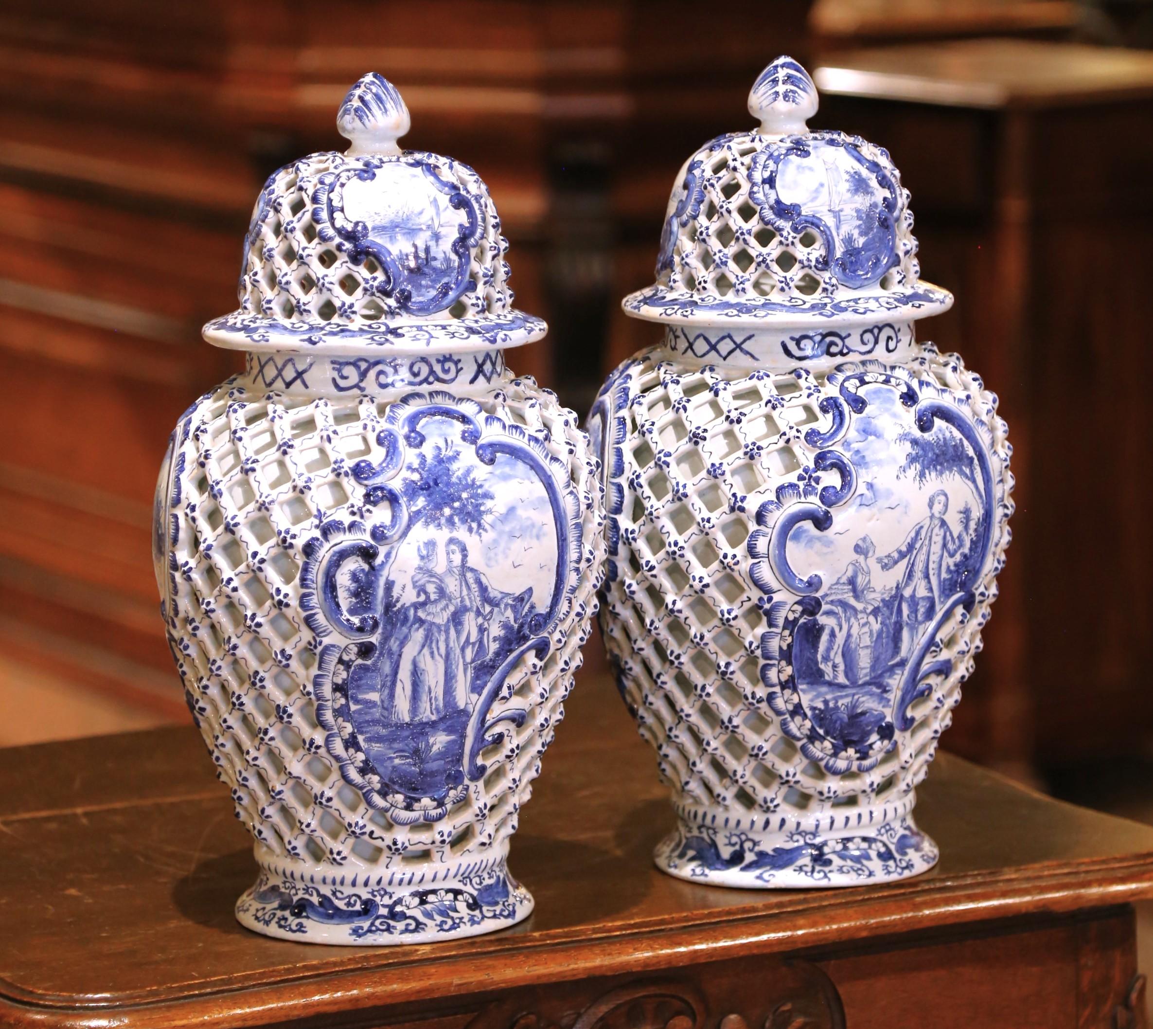 This striking pair of faïence vases was crafted in France circa 1880 in the Delft style and features hand-painted blue and white decoration on a finely reticulated ground. Each baluster-form vessel is pierced with a lattice motif, framed by