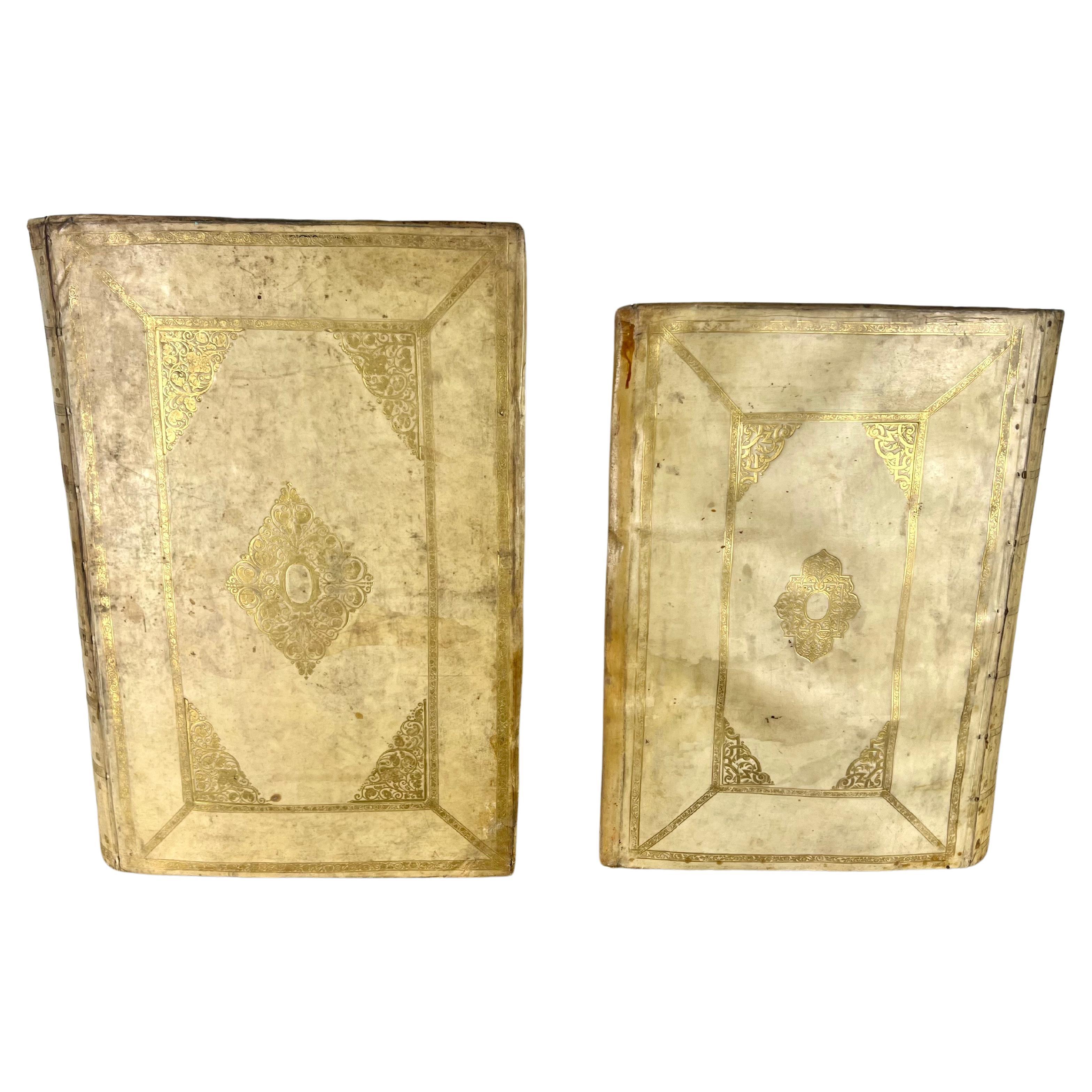 Two containers made from antique velum books. They are triangular in shape, each adorned with a faded golden design against a lighter background.  The diamond-shaped central motif, bordered by intricate patterns, suggests a touch of elegance and