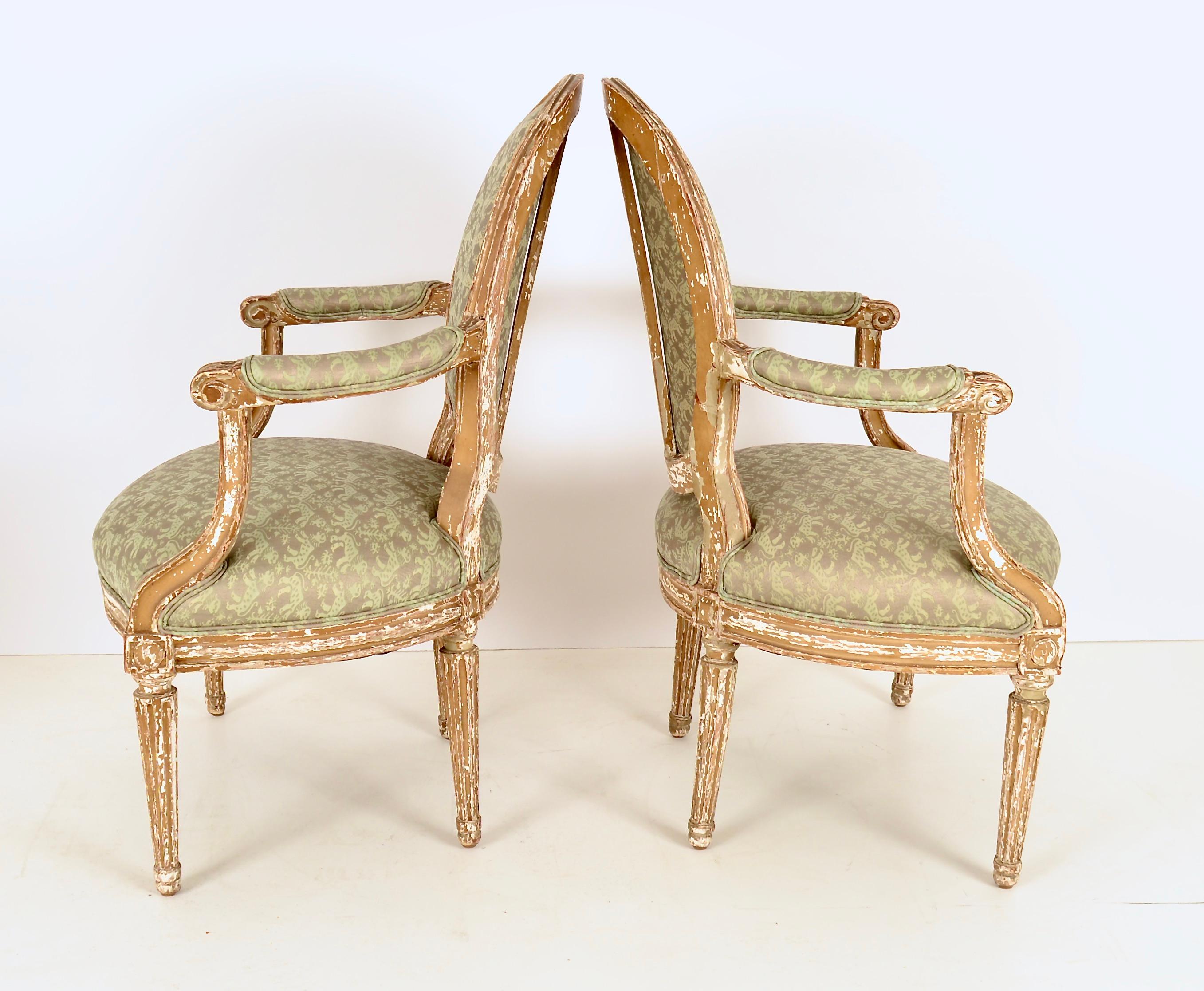 Charming pair of 19th century fauteuil chairs with attractive distressed paint finish. Now reupholstered in printed Fortuny fabric in soft green and gold.
