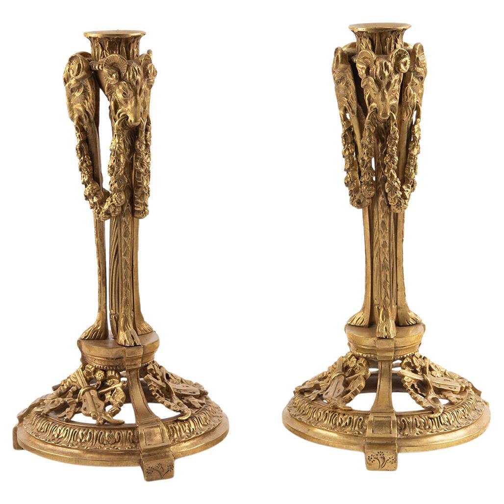 Coppia di candelieri a testa d'ariete in bronzo dorato francese del XIX secolo con motivi musicali in vendita