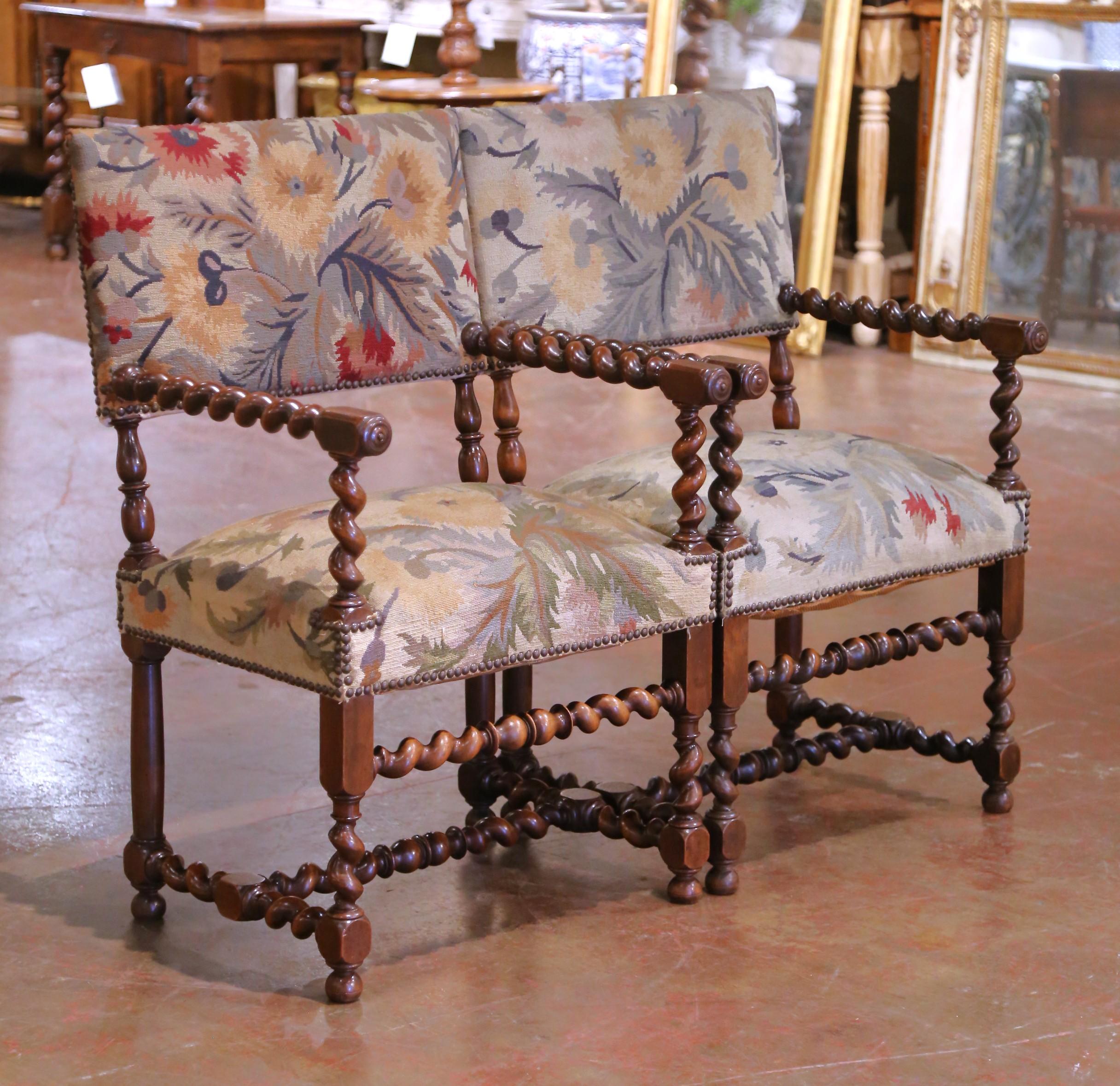 Add sophistication and texture to your interior with this elegant pair of antique armchairs, crafted in France circa 1880. Each chair is made of solid walnut and features hand-carved barley twist legs, stretchers, and arm supports, all hallmarks of