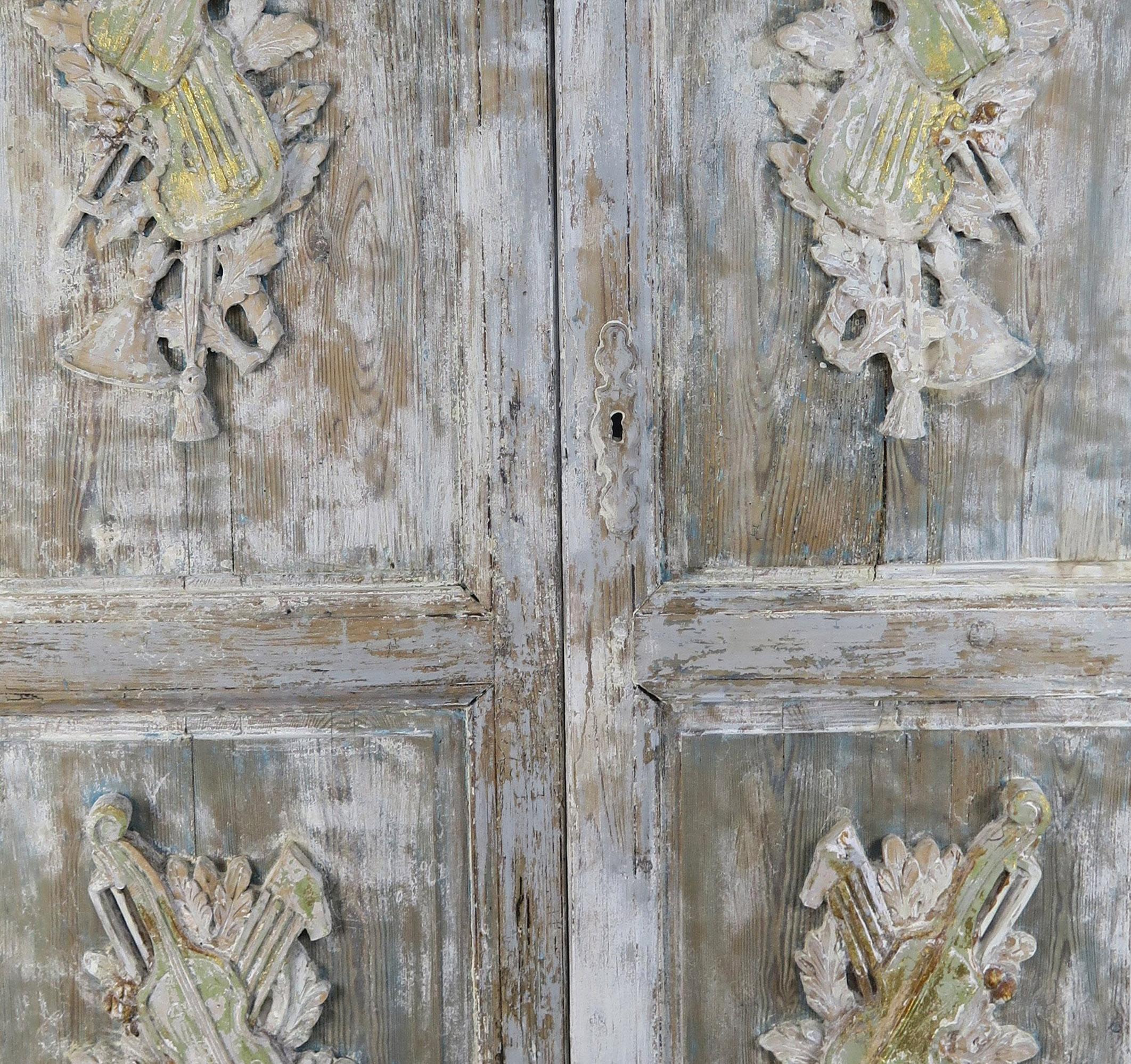 Pair of 19th century French Louis XV style carved painted doors with carvings of musical instruments on all four panels. Beautiful painted distressed finish in soft shades of gray, antique white and gold.