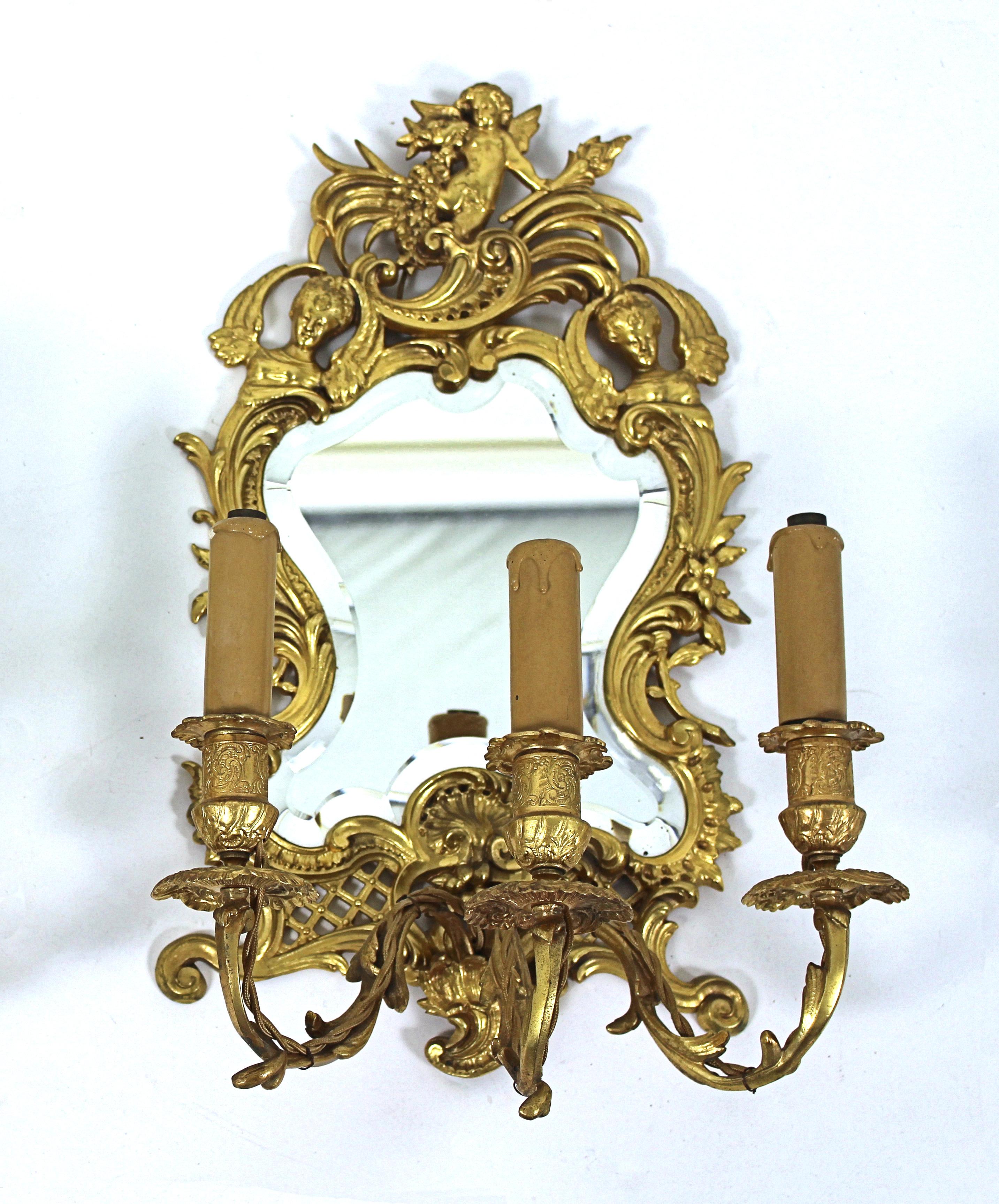 These very attractive and decorative pair of 19th century French ormolu Girondelles that have been fitted for electricity are decorated with winged figures and feature 3 candelabra arms with candlestick motifs. The shaped mirror backs are bevelled